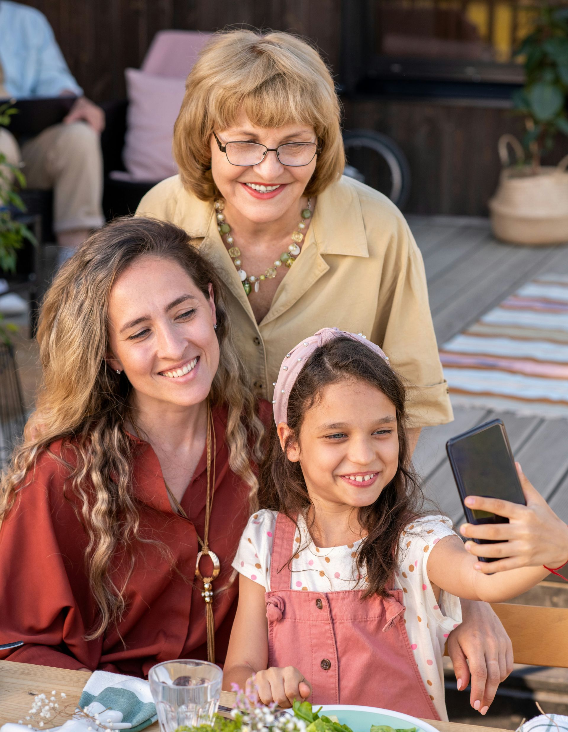 A woman is taking a selfie with her family while sitting at a table.