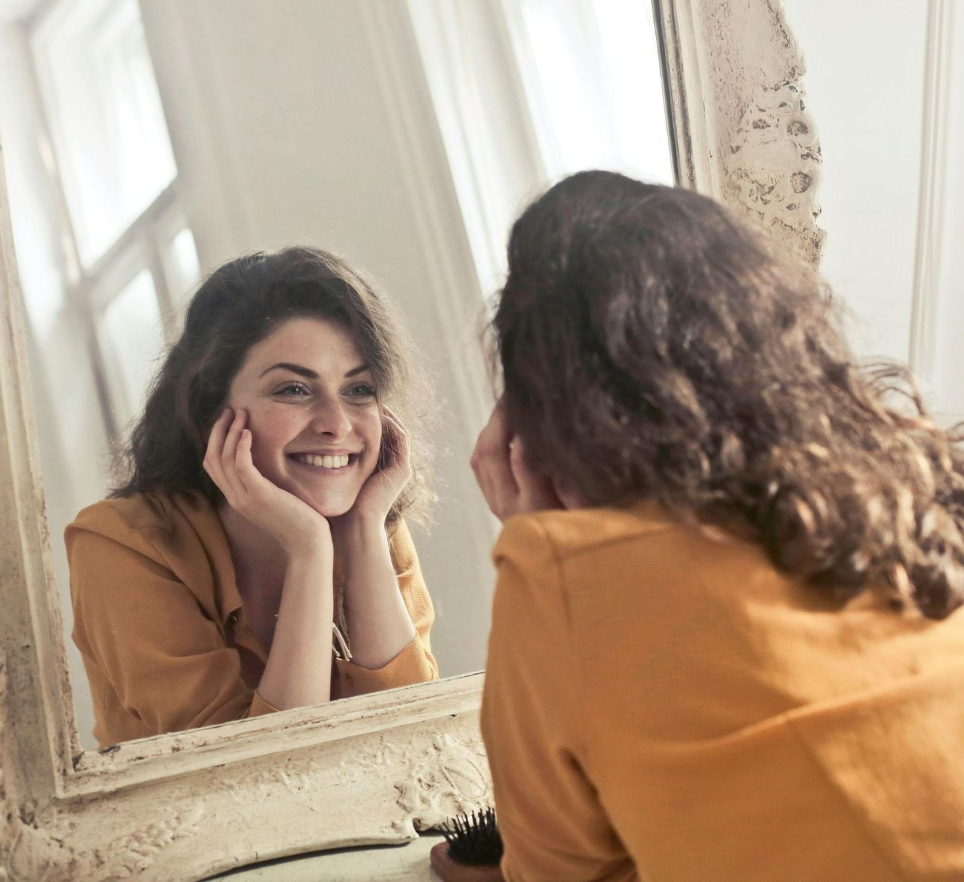 A woman is smiling while looking at herself in a mirror.