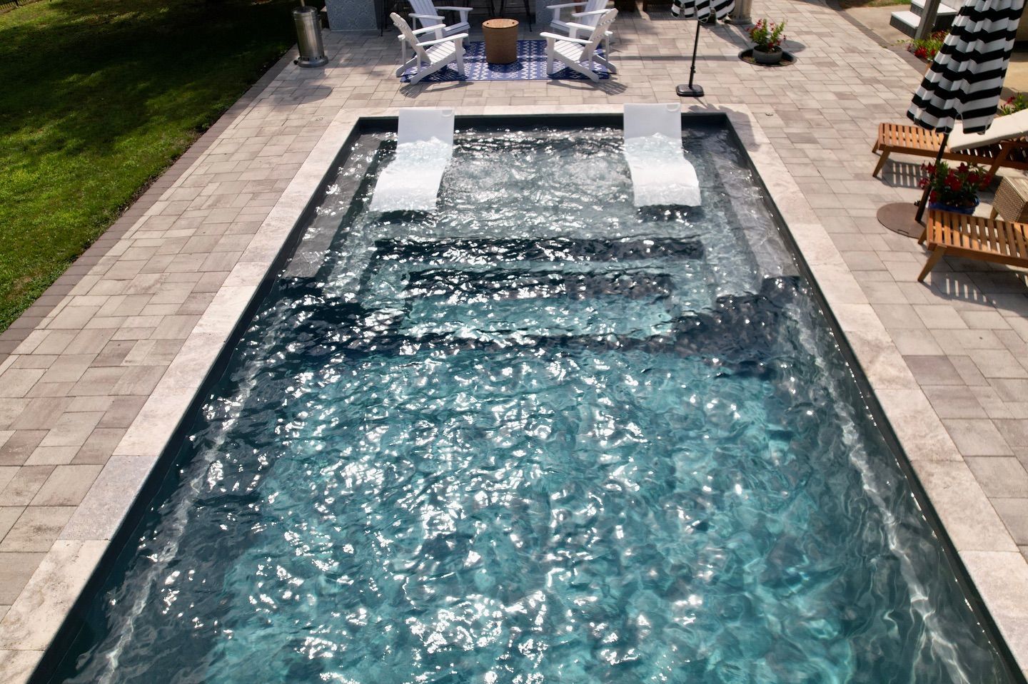 An aerial view of a large swimming pool surrounded by chairs and umbrellas.