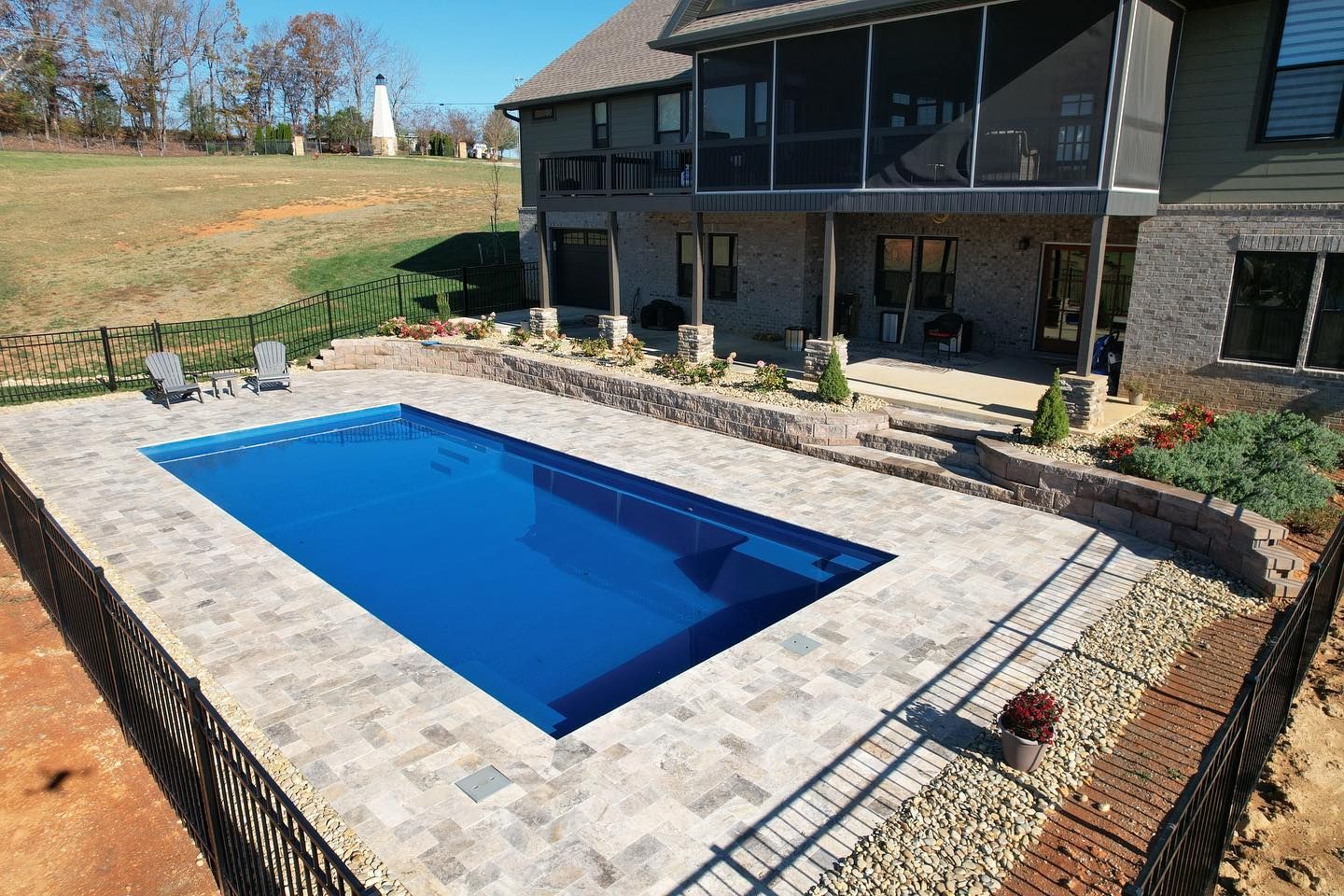 There is a large swimming pool in the backyard of a house.
