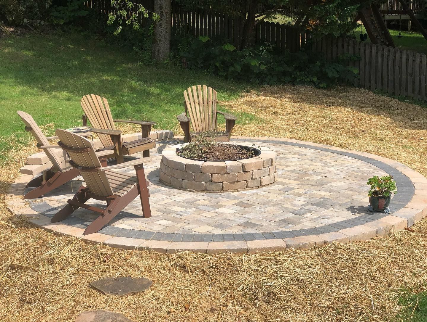 A fire pit in the middle of a patio with chairs around it.