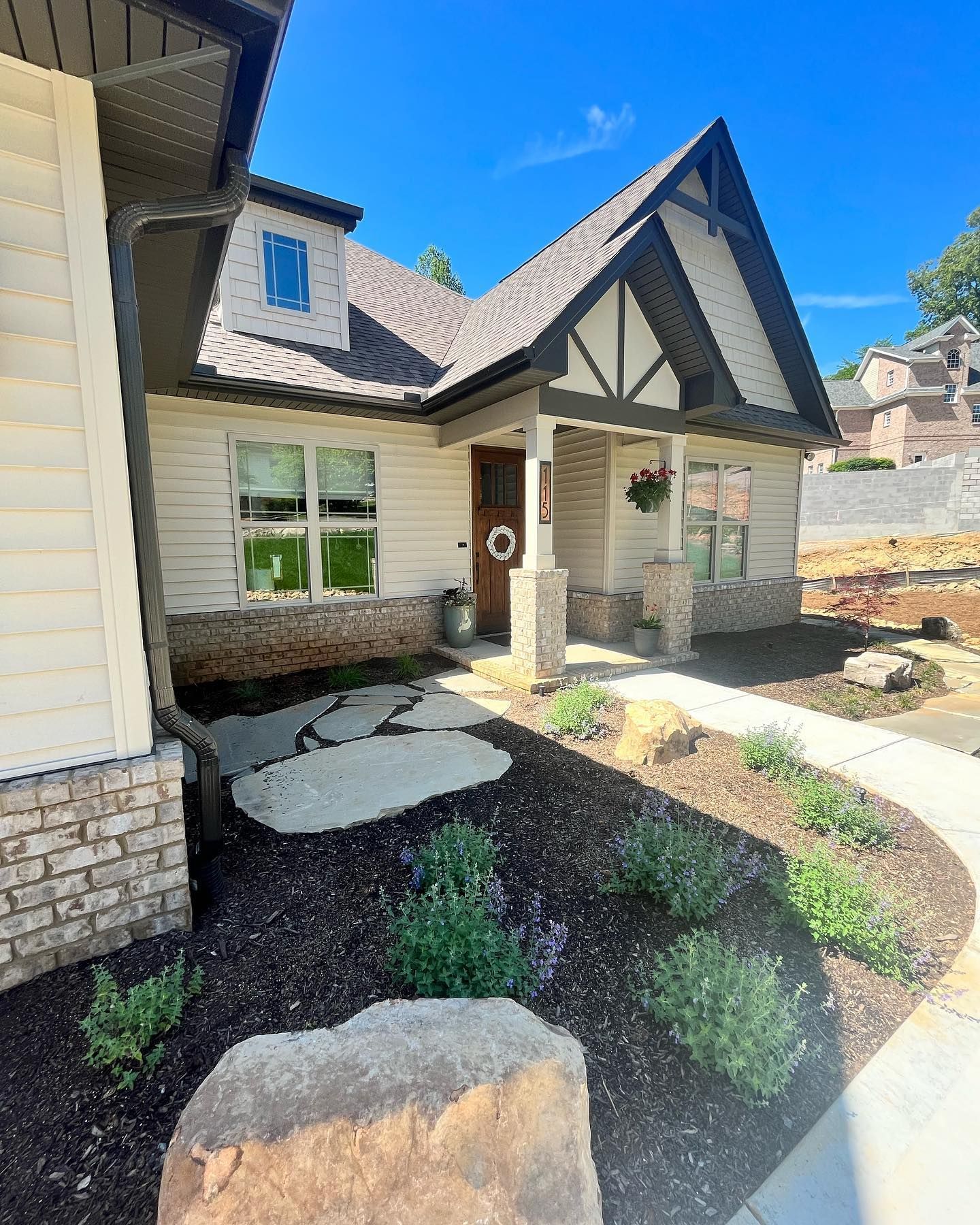 A white house with a brown door and a walkway leading to it.