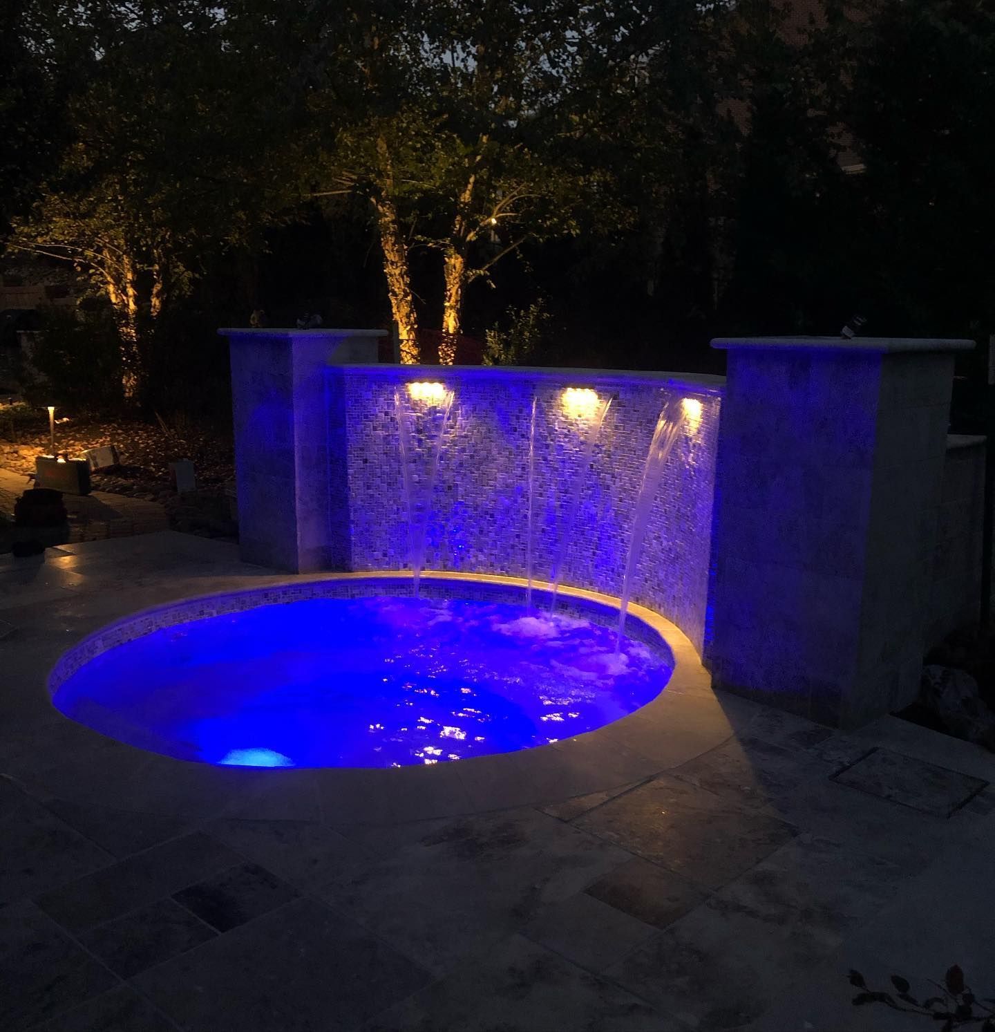 A swimming pool is lit up with blue lights at night