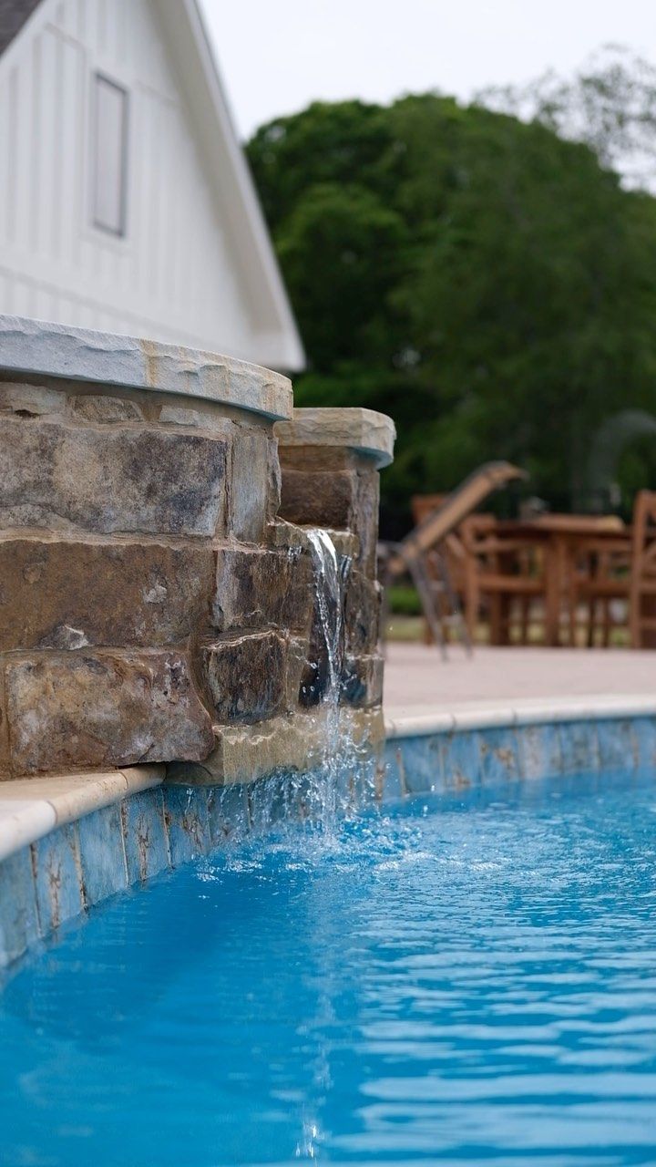There is a waterfall in the middle of a swimming pool.