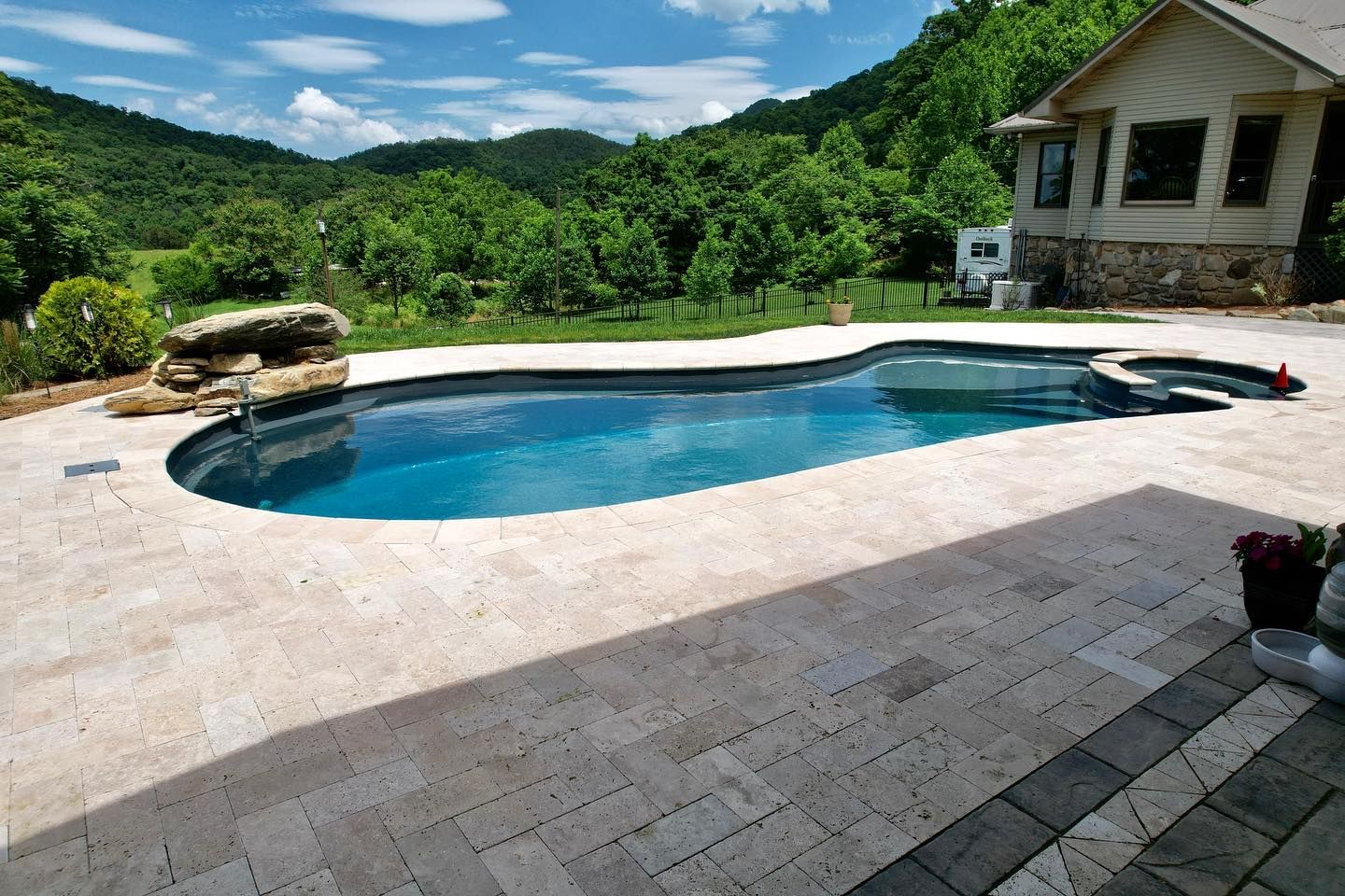 A large swimming pool is surrounded by a patio and mountains in the background.
