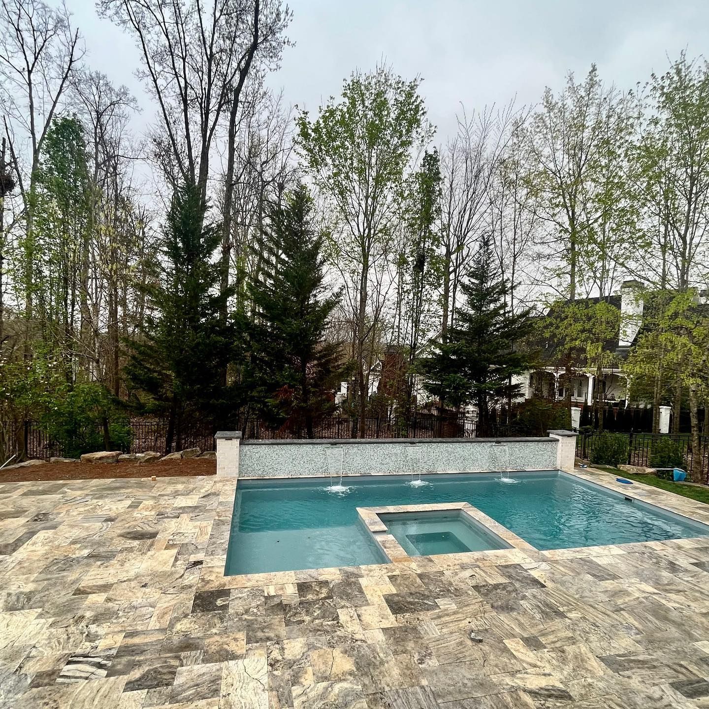 A large swimming pool surrounded by trees in a backyard.