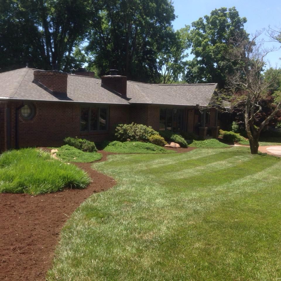 A brick house with a lush green lawn in front of it