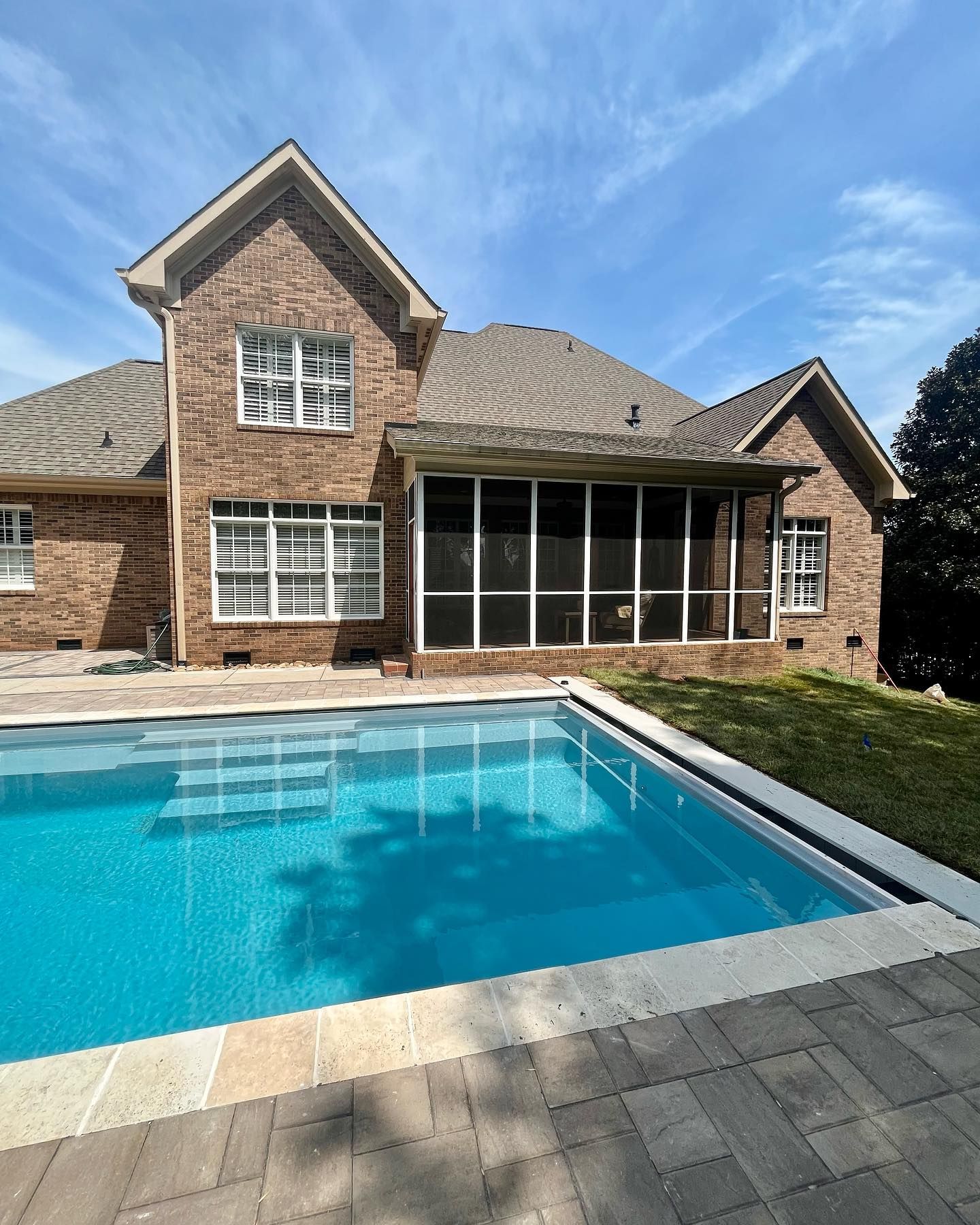 A large brick house with a swimming pool in front of it.