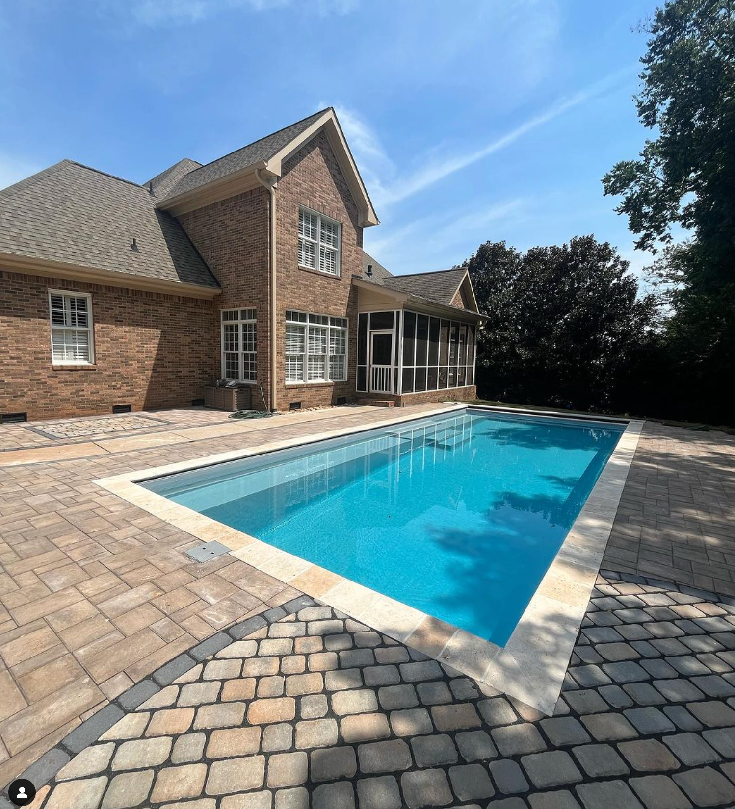 A large brick house with a large swimming pool in front of it