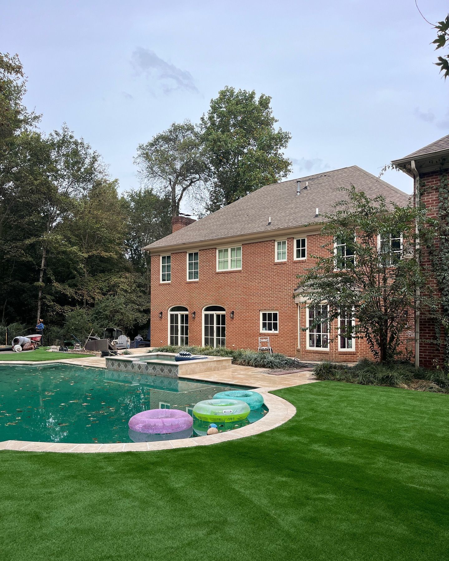 A large brick house with a large swimming pool in front of it.