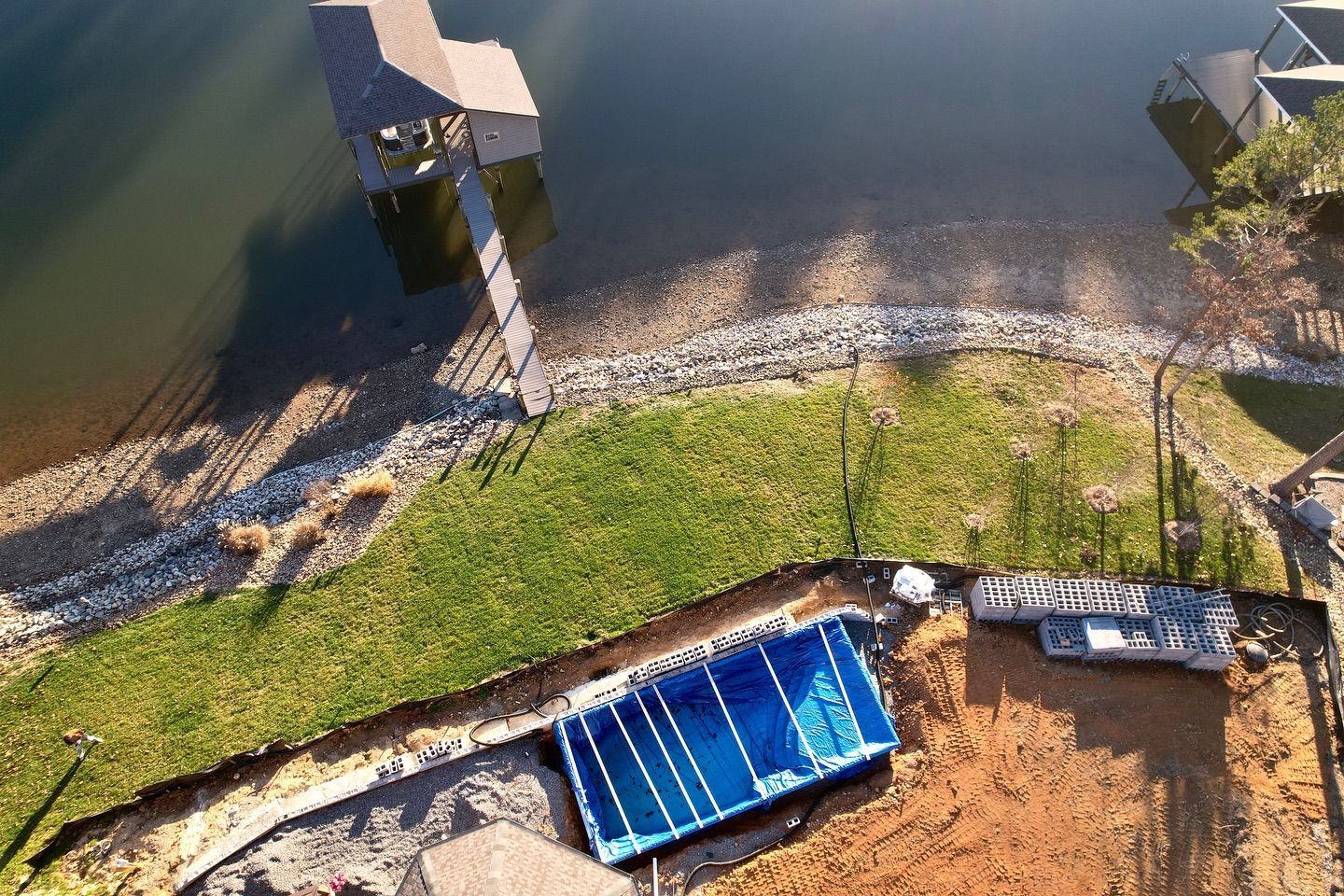 An aerial view of a swimming pool being built next to a body of water.
