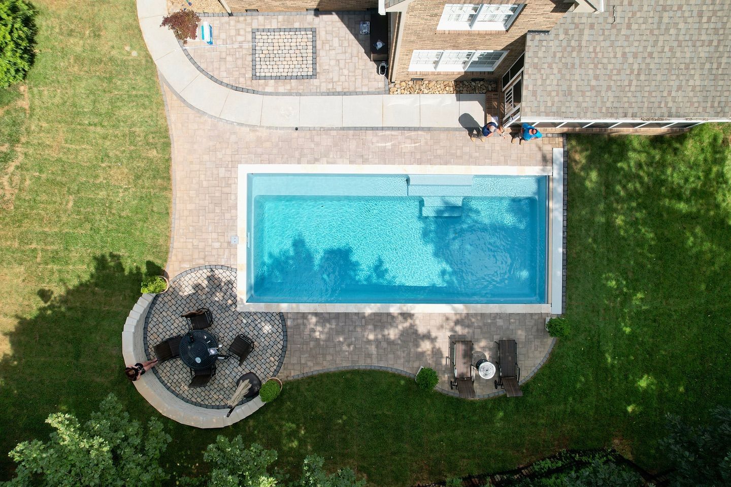 An aerial view of a large swimming pool in the backyard of a house.