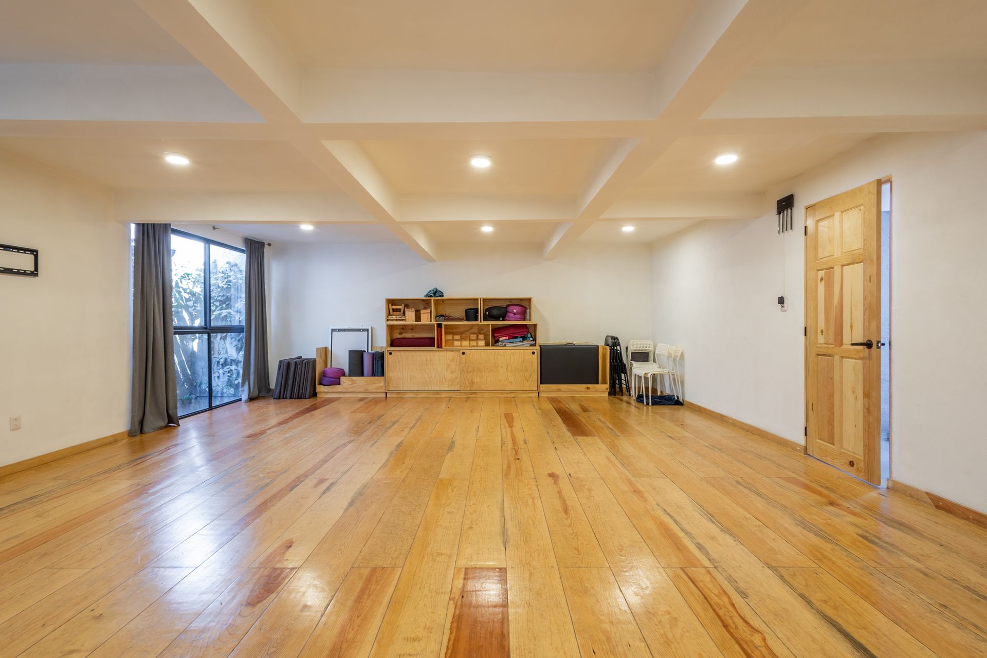 Una gran habitación vacía con suelos de madera y paredes blancas.