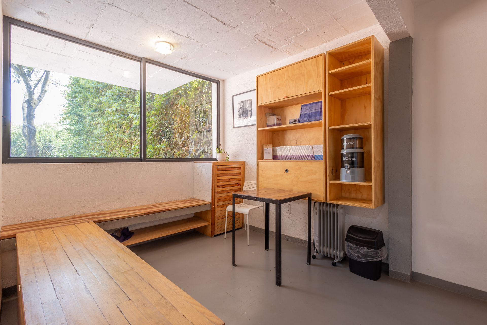 Una habitación con una mesa, estantes y una ventana.