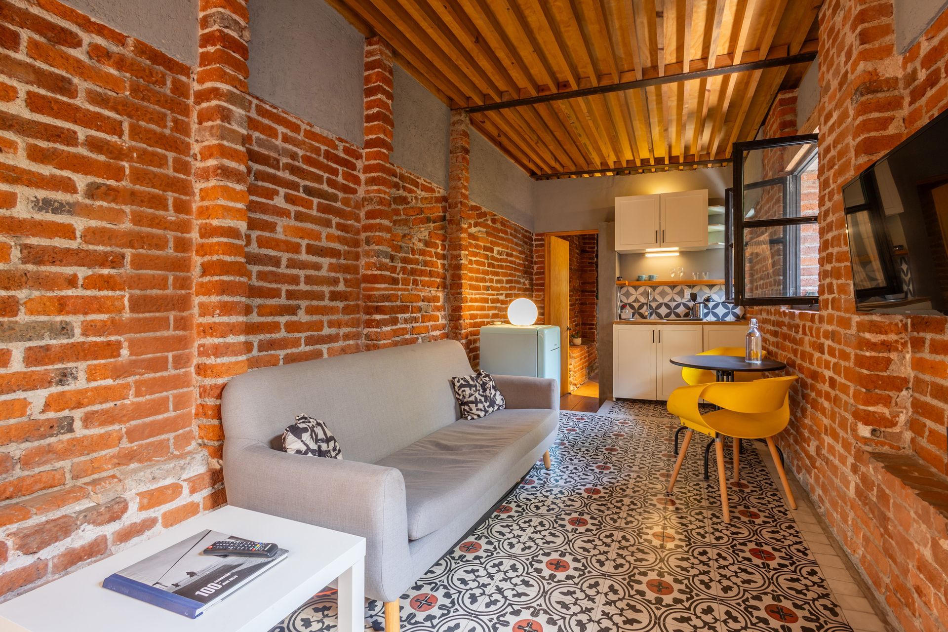 Una sala de estar con sofá, mesa, sillas y paredes de ladrillo.