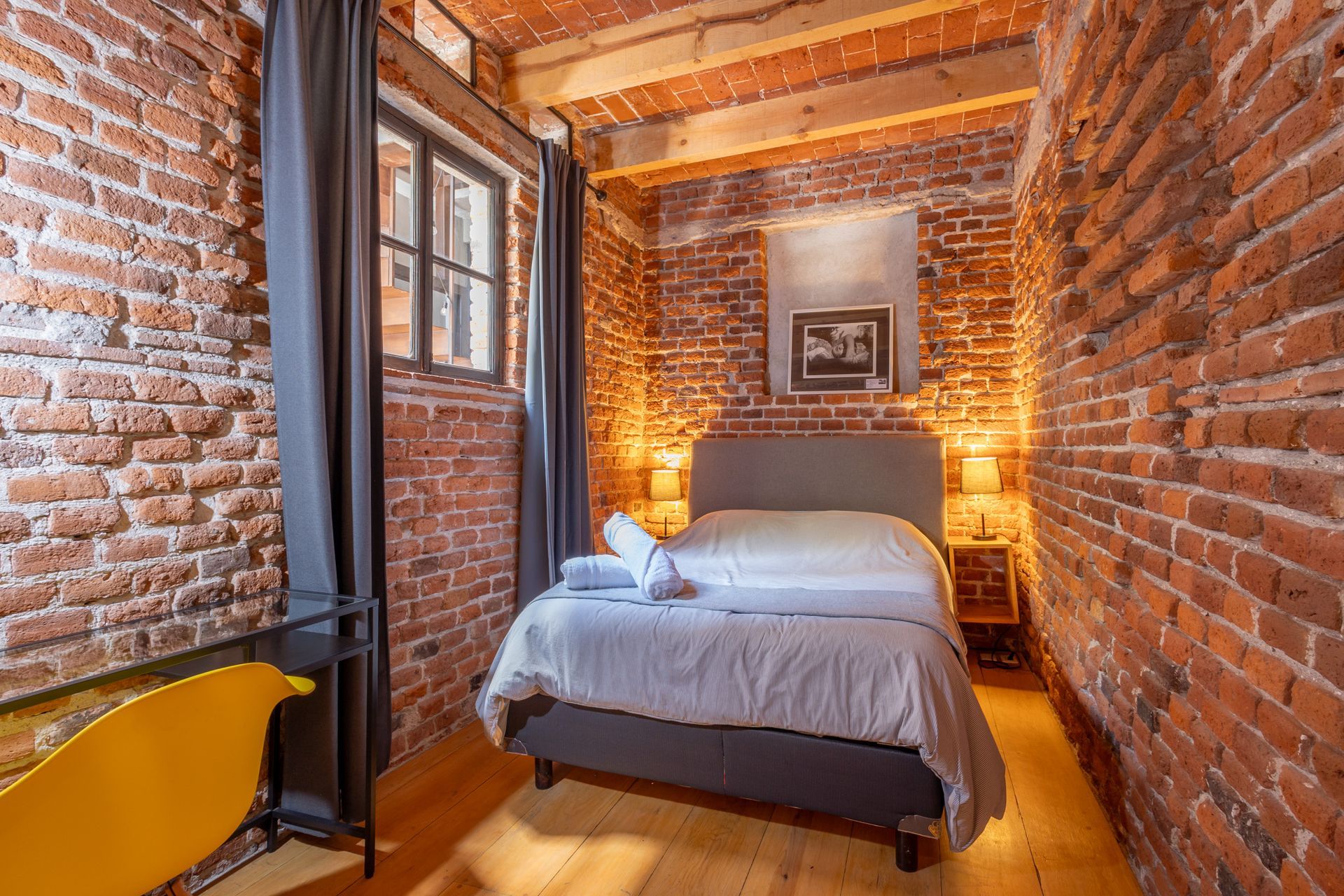 Un dormitorio con una cama y una pared de ladrillos.