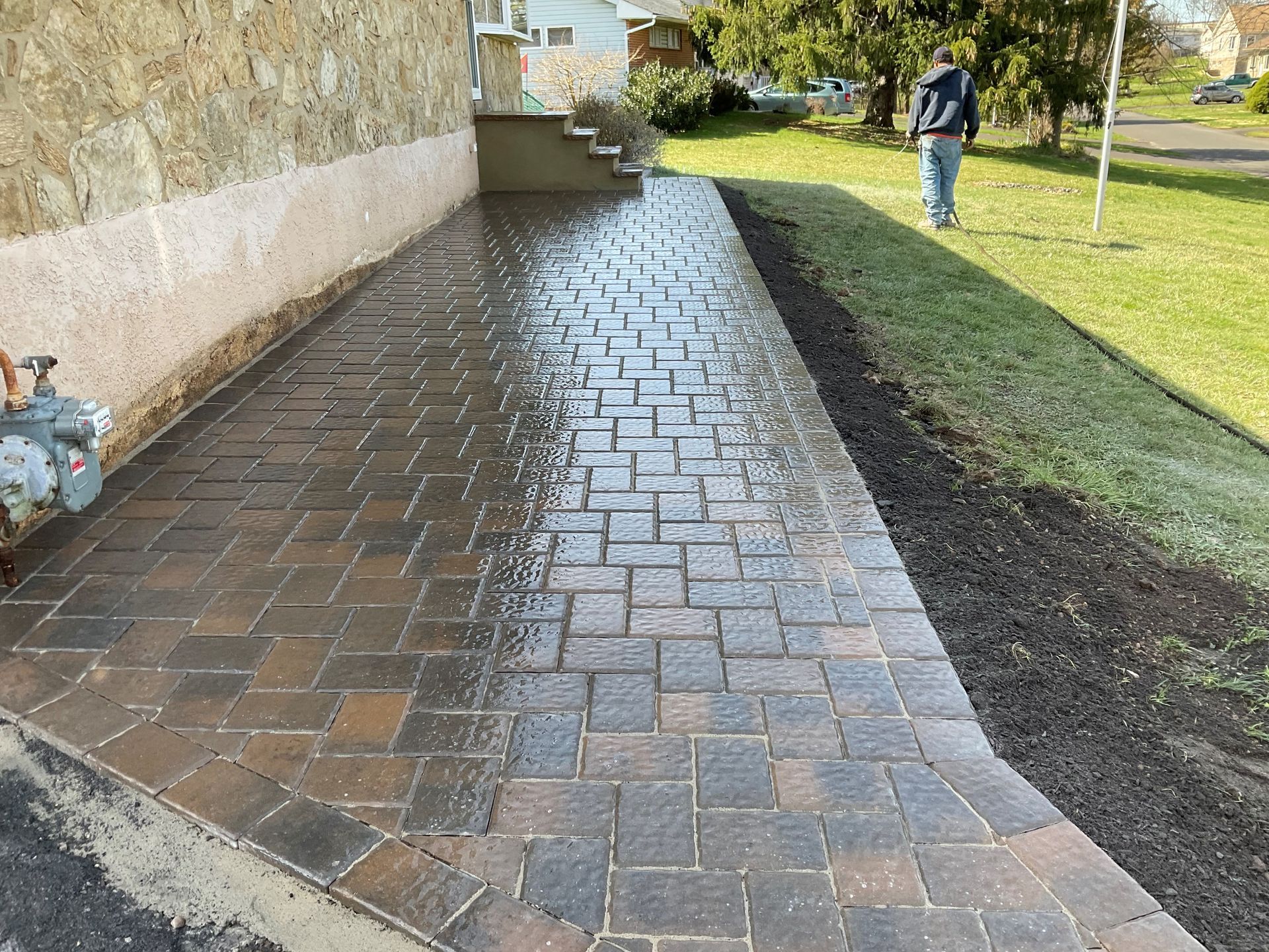 A Man Is Walking Down a Sidewalk Next to A House.