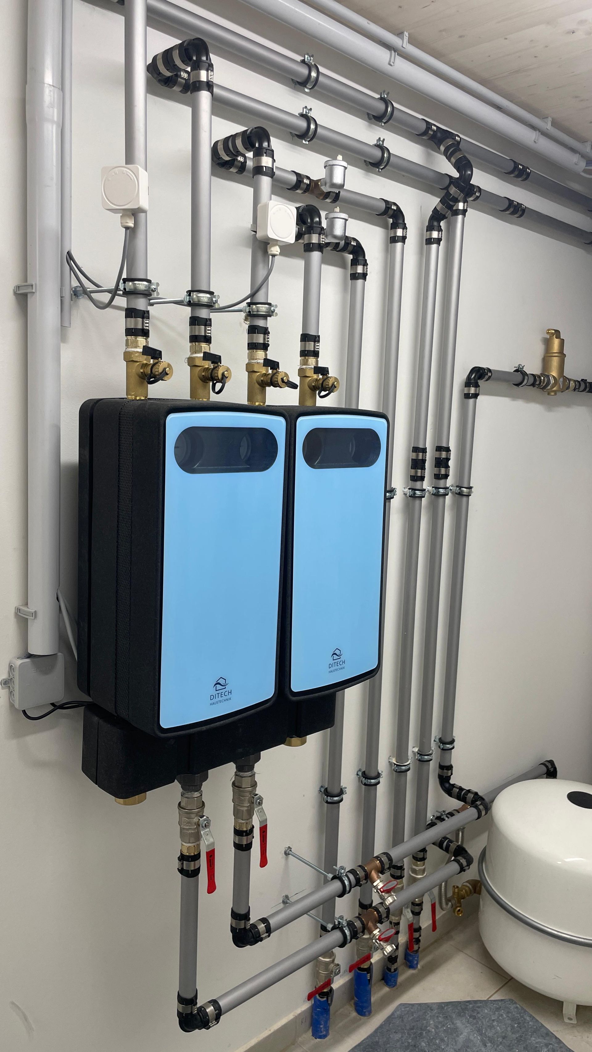 Blaue Klimaanlagen sind an einer Wand montiert, dazu silberne Rohre und Ventile. 