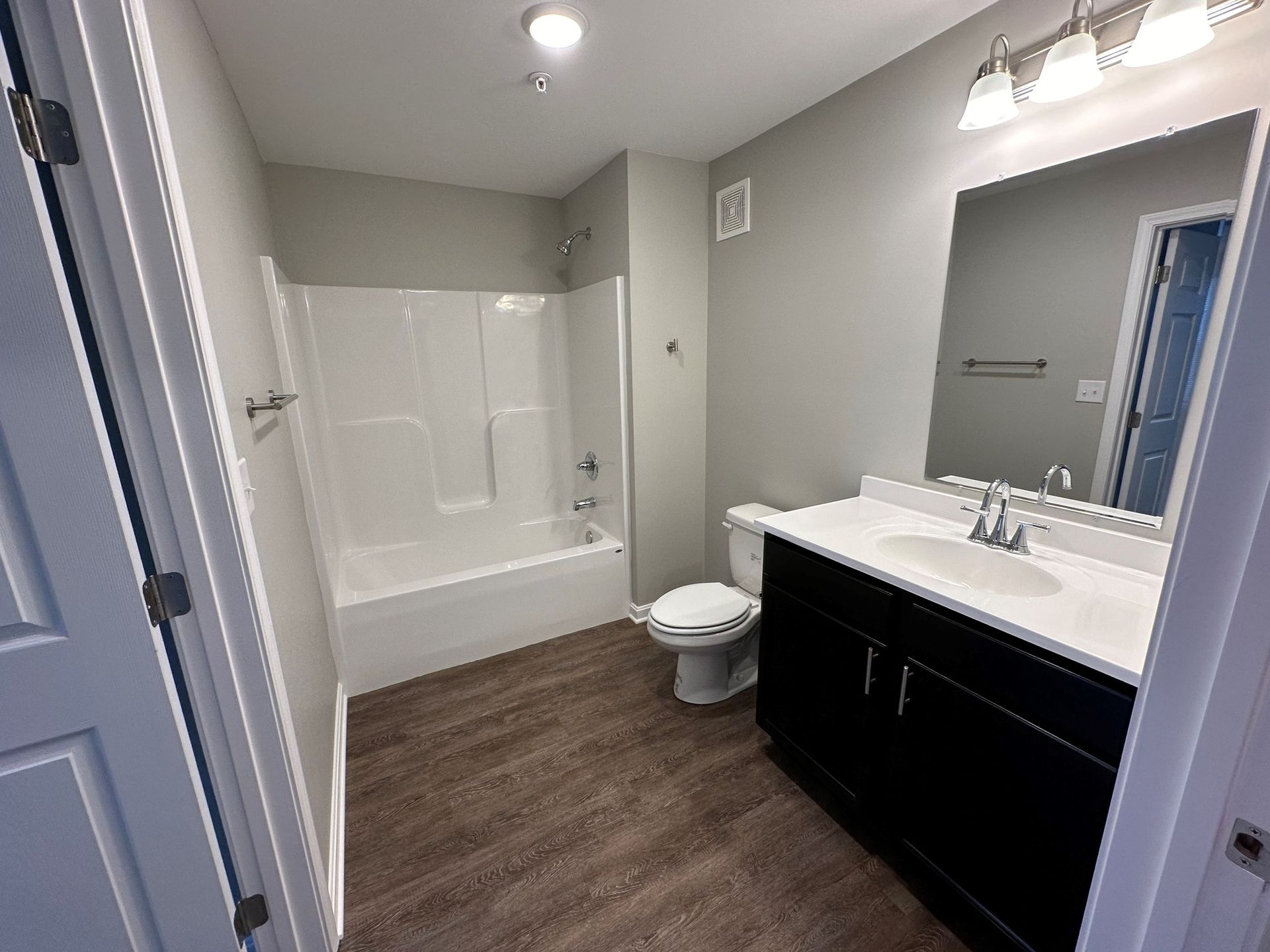 A bathroom with a sink , toilet , bathtub and mirror.