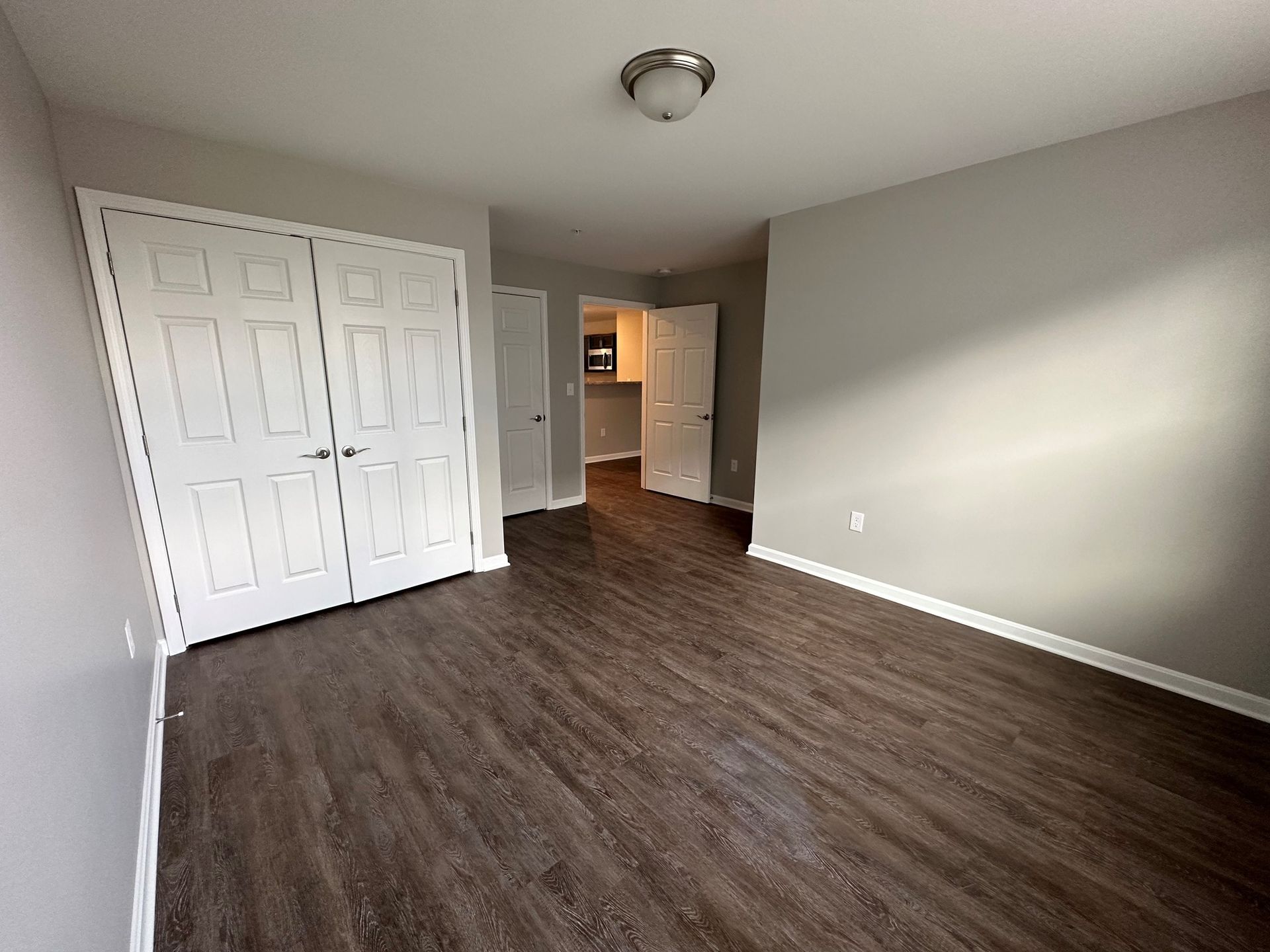 A large empty room with hardwood floors and a closet.