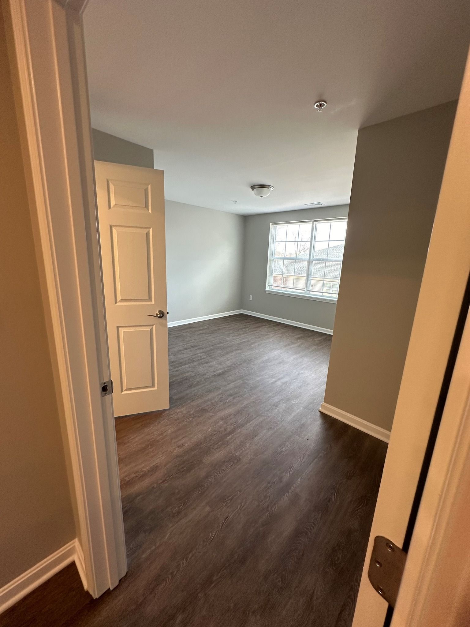 A large empty room with hardwood floors and a window.