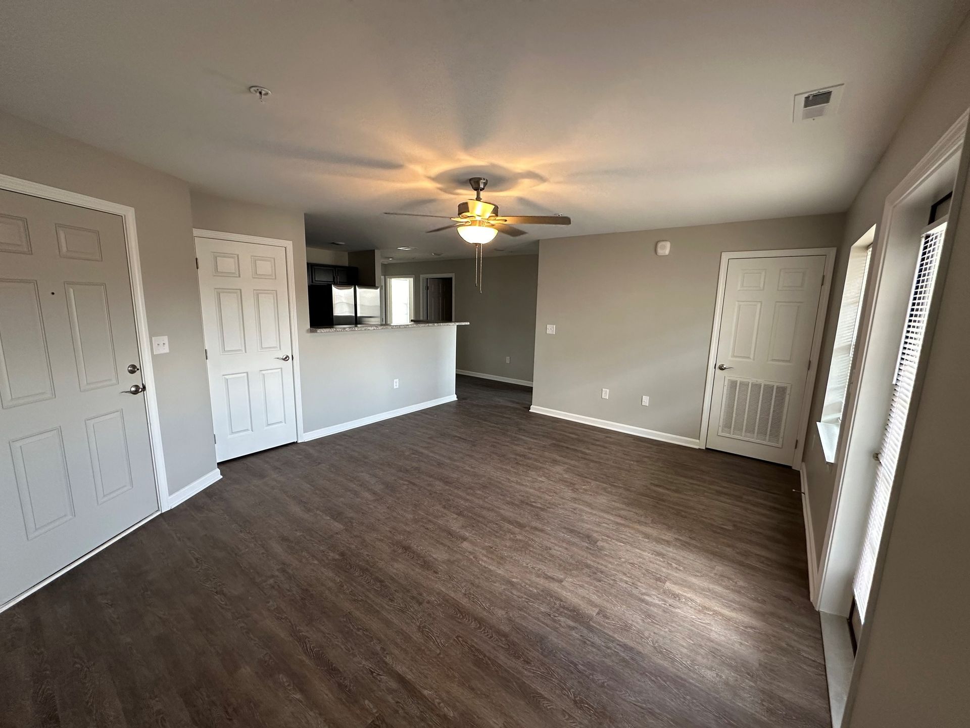 An empty living room with hardwood floors and a ceiling fan.