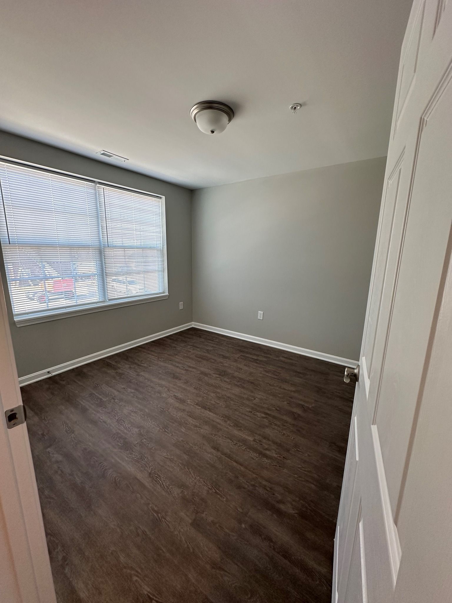 An empty bedroom with hardwood floors and a window.