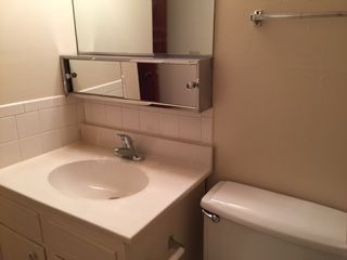 A bathroom with a sink , toilet and mirror.