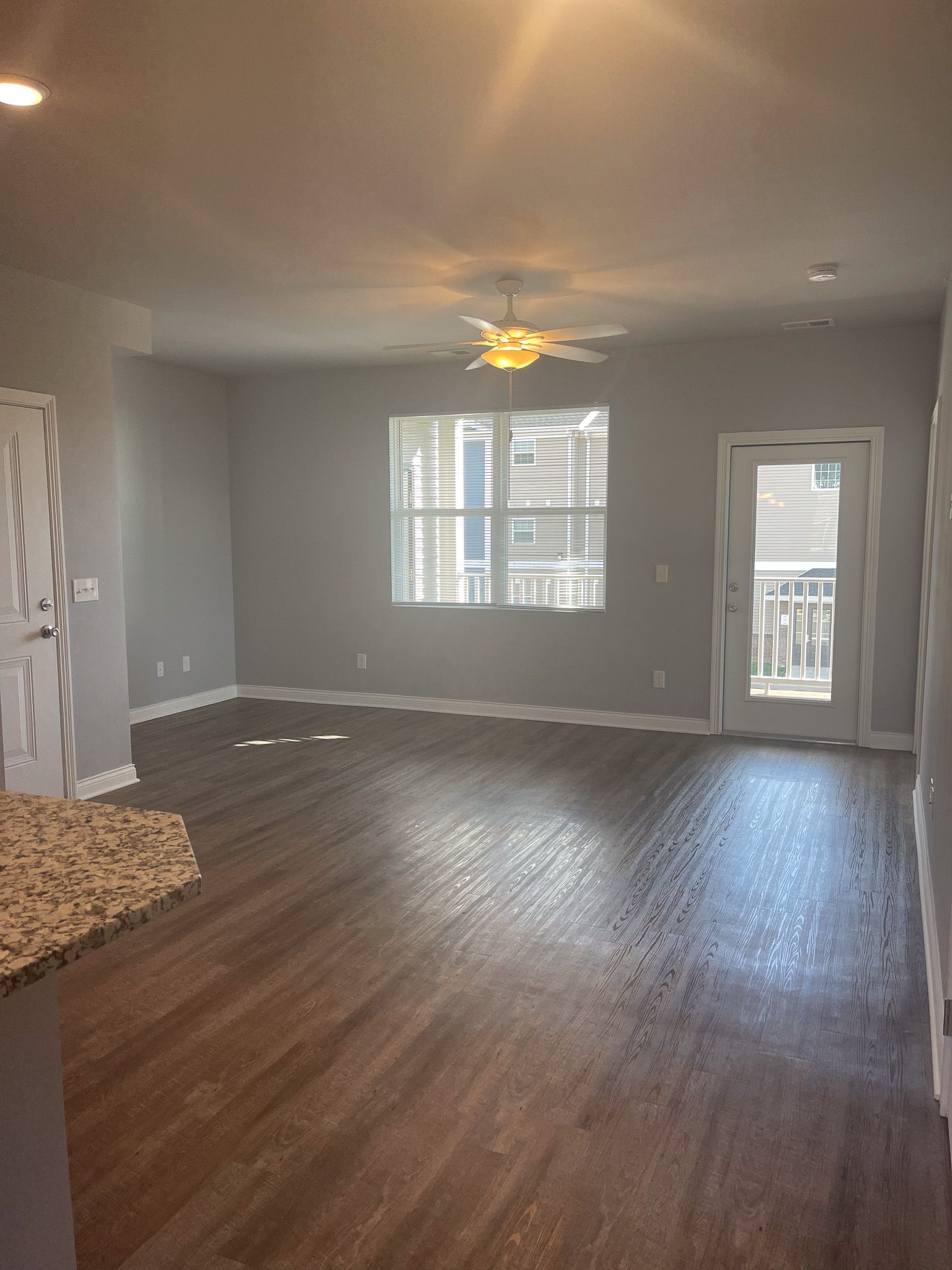 An empty living room with hardwood floors and a ceiling fan.