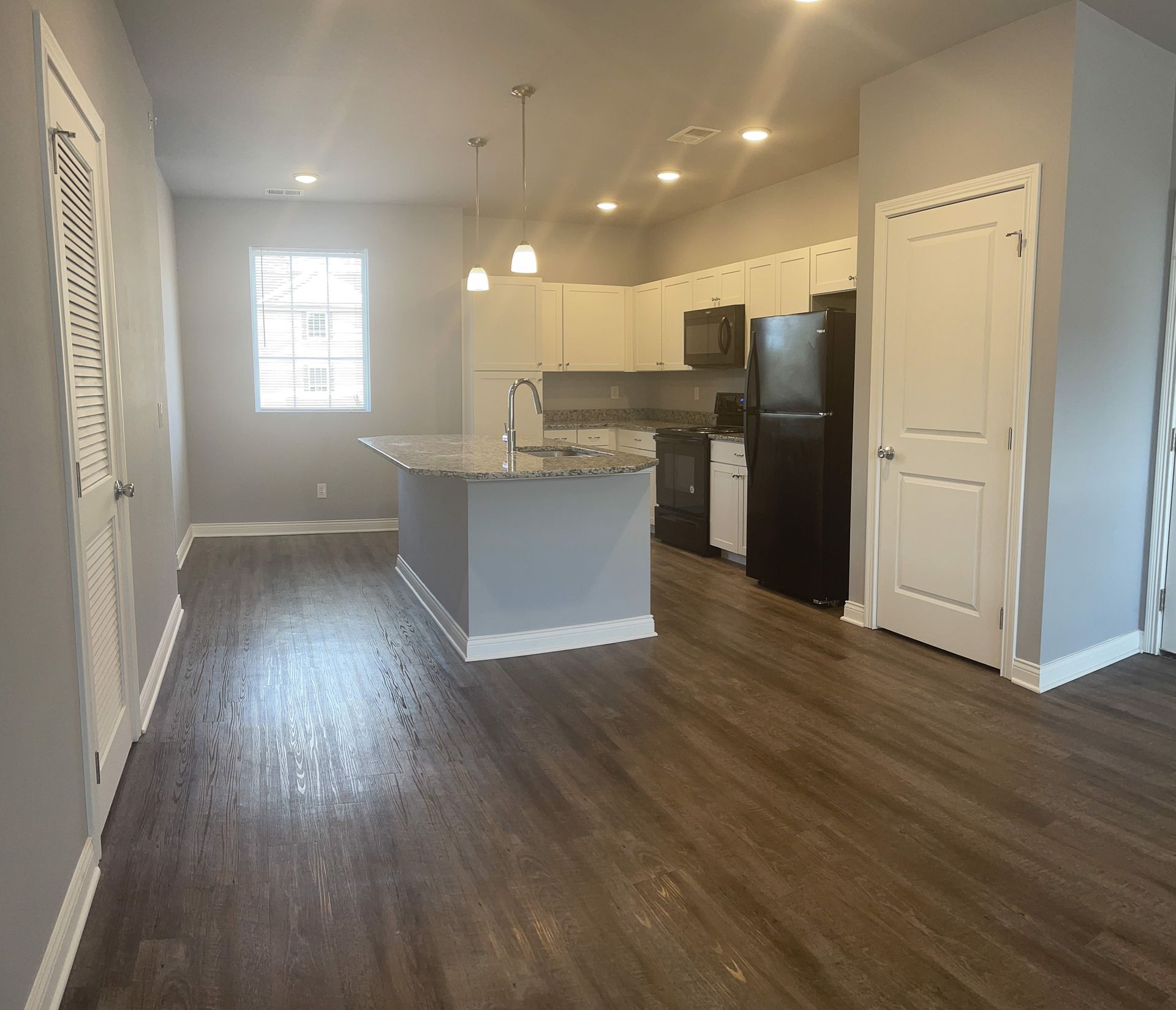 A kitchen with a large island and a refrigerator in a house.