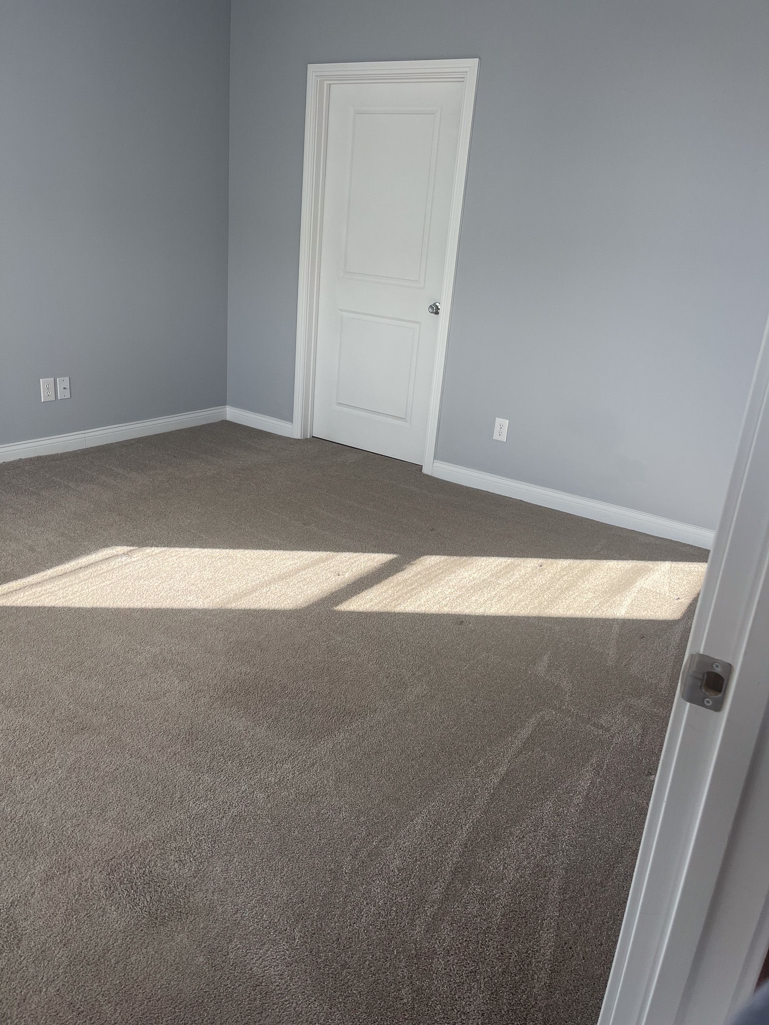 A room with a carpeted floor and a white door.
