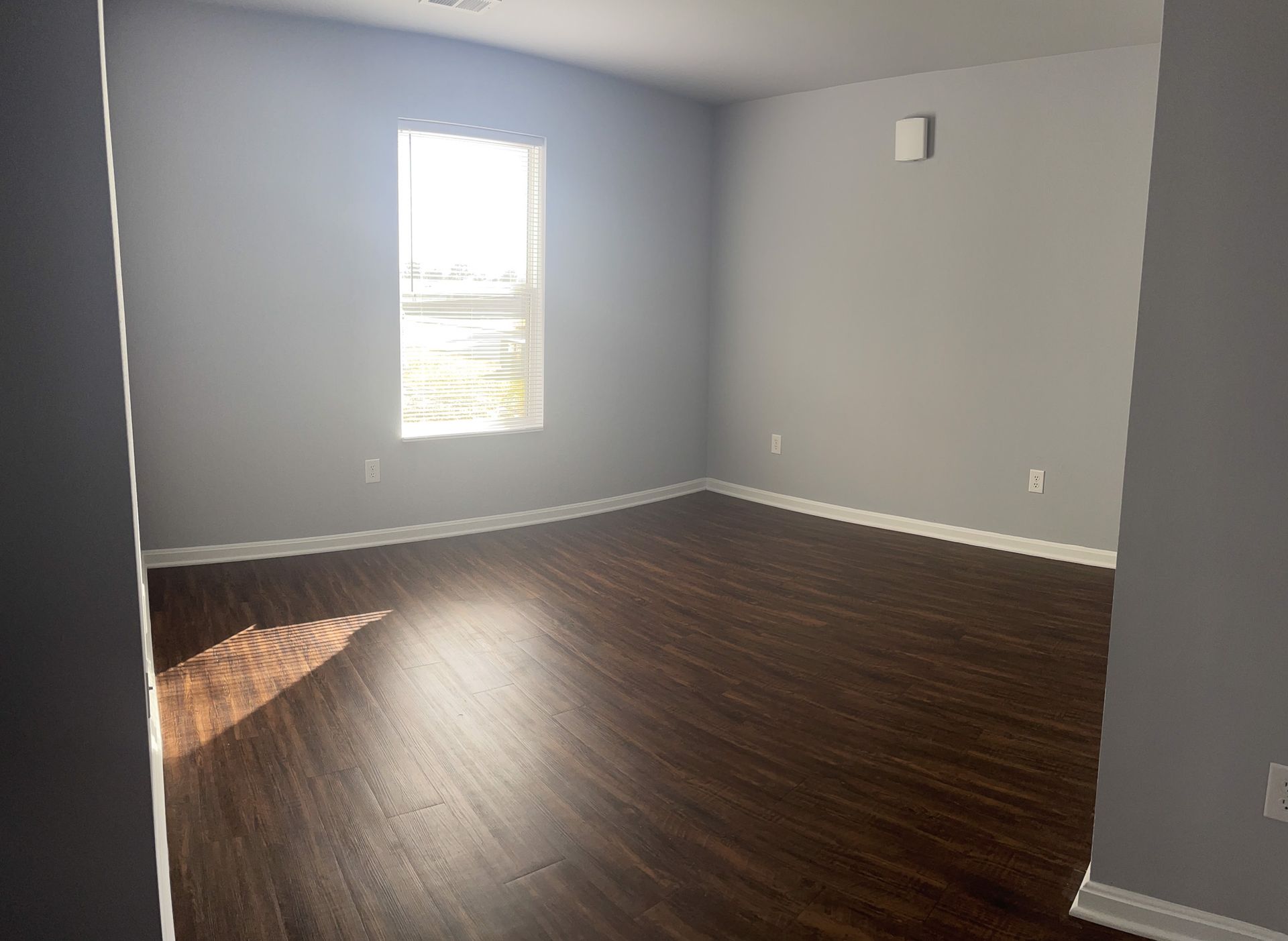 An empty living room with hardwood floors and a window.