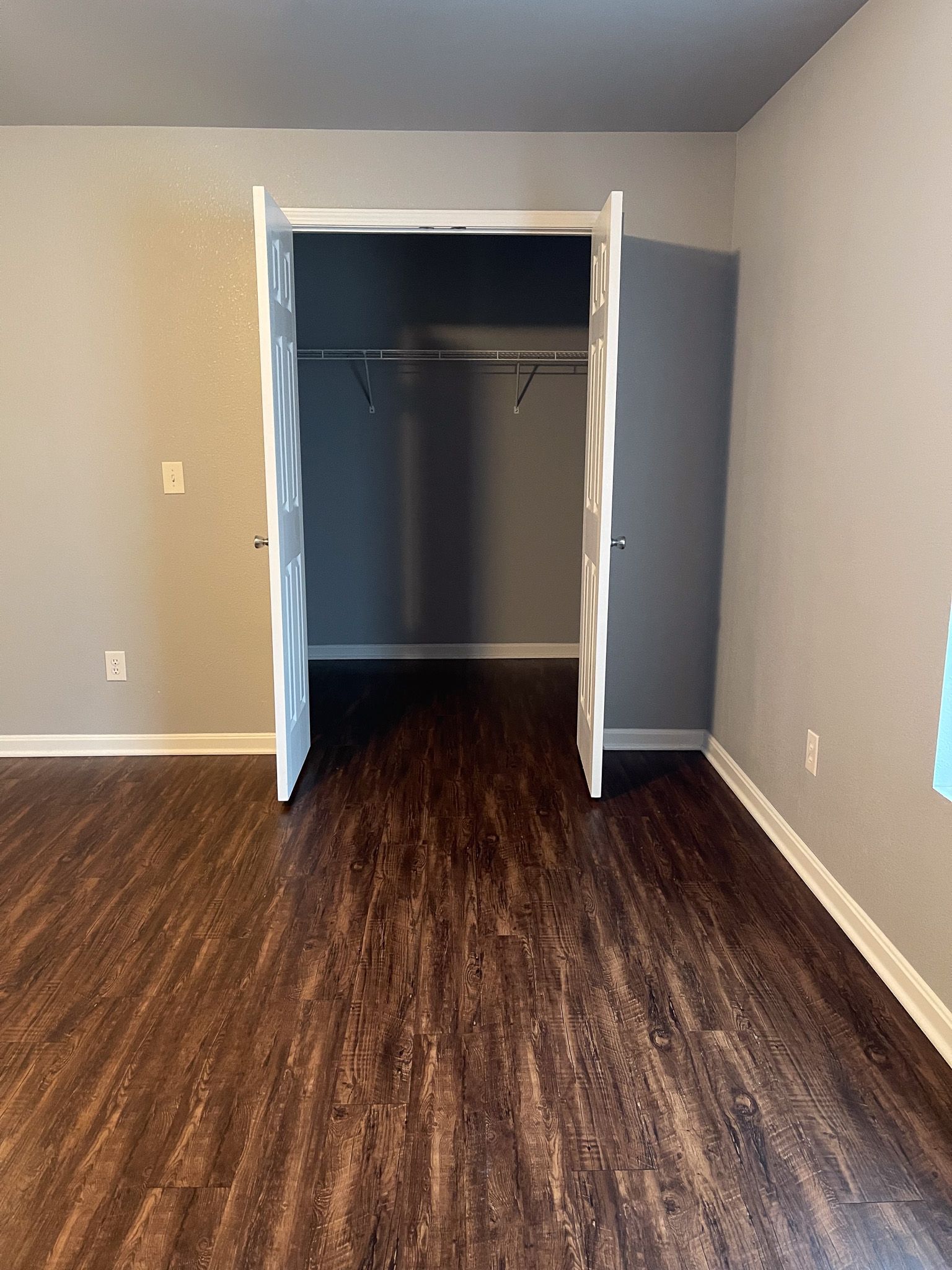 An empty bedroom with hardwood floors and a closet.