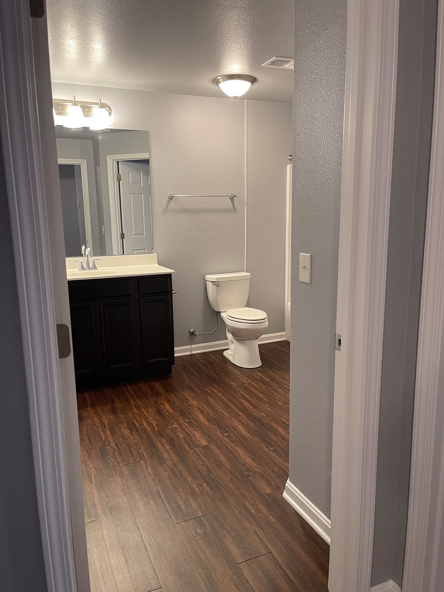 A bathroom with a toilet , sink and mirror.