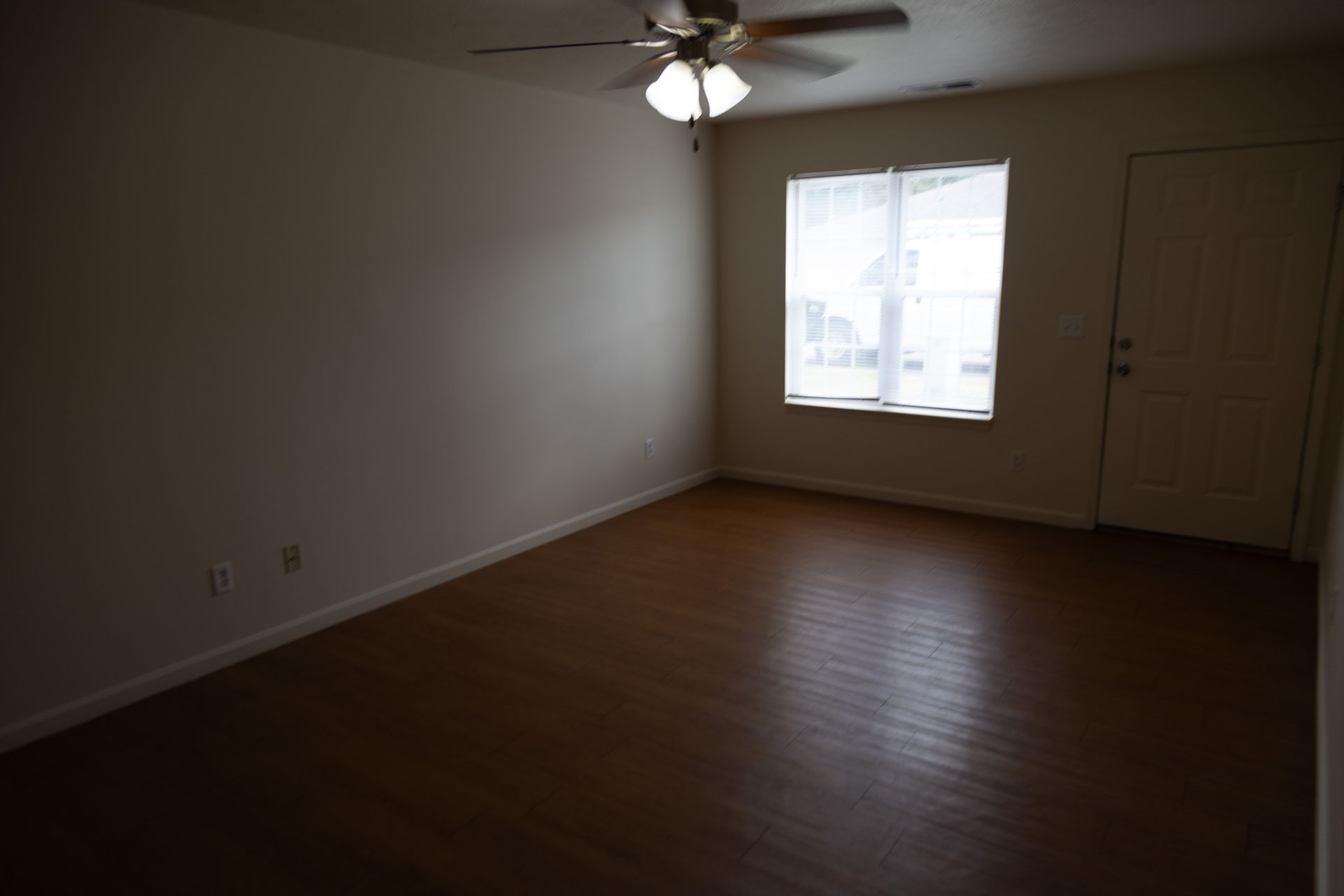 An empty living room with a ceiling fan and a window