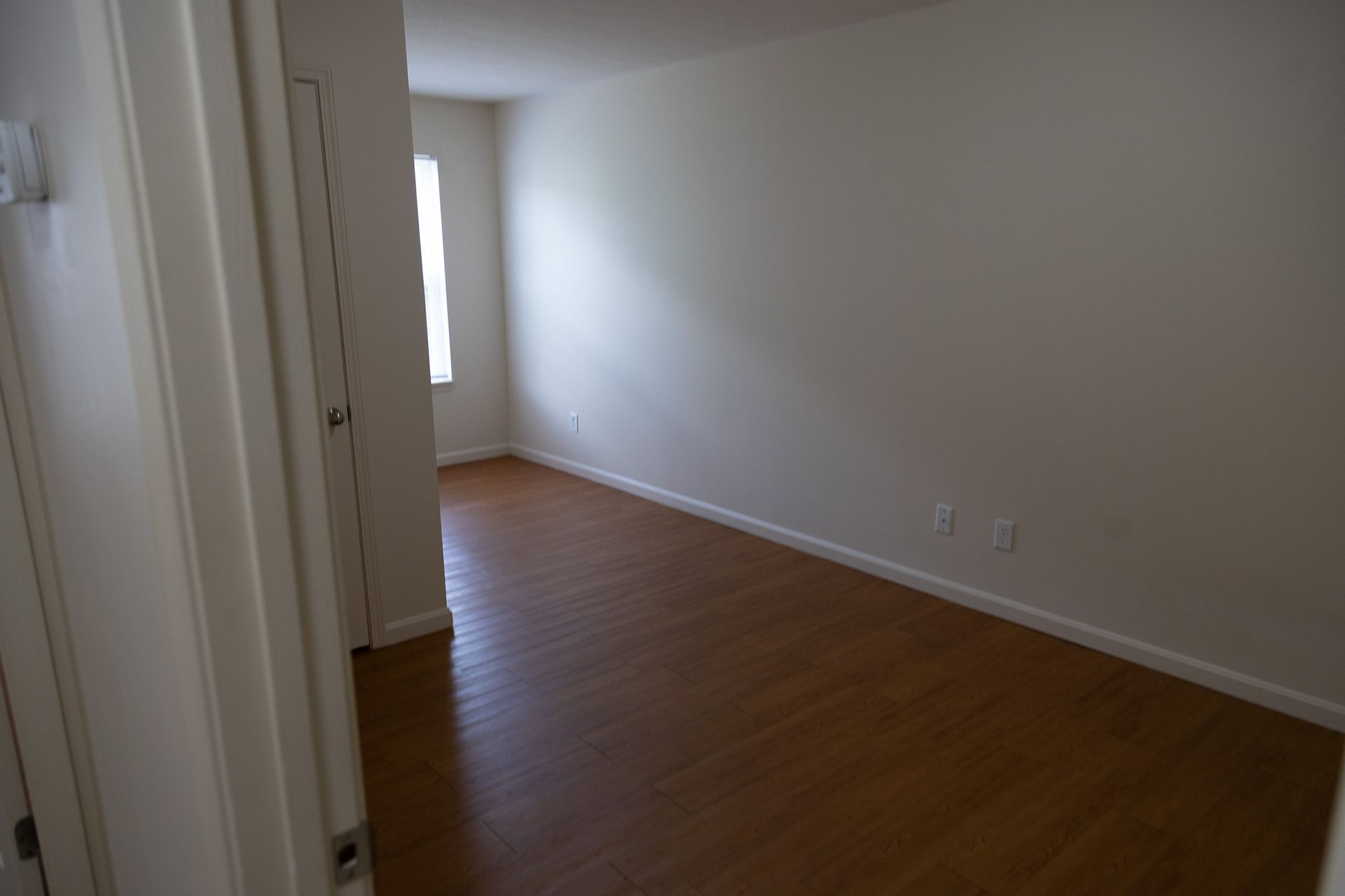 An empty living room with hardwood floors and white walls.