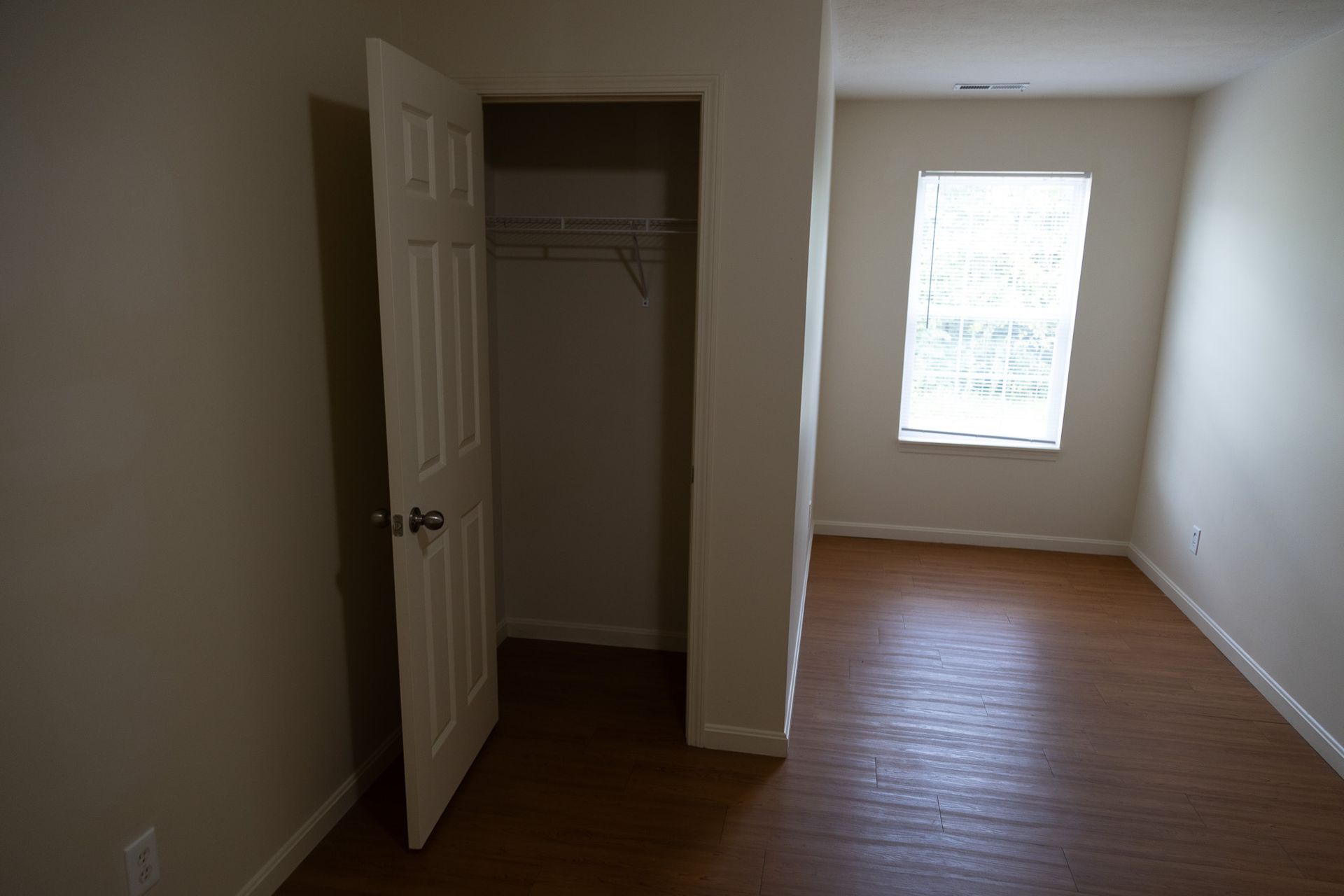 An empty bedroom with a closet and a window.
