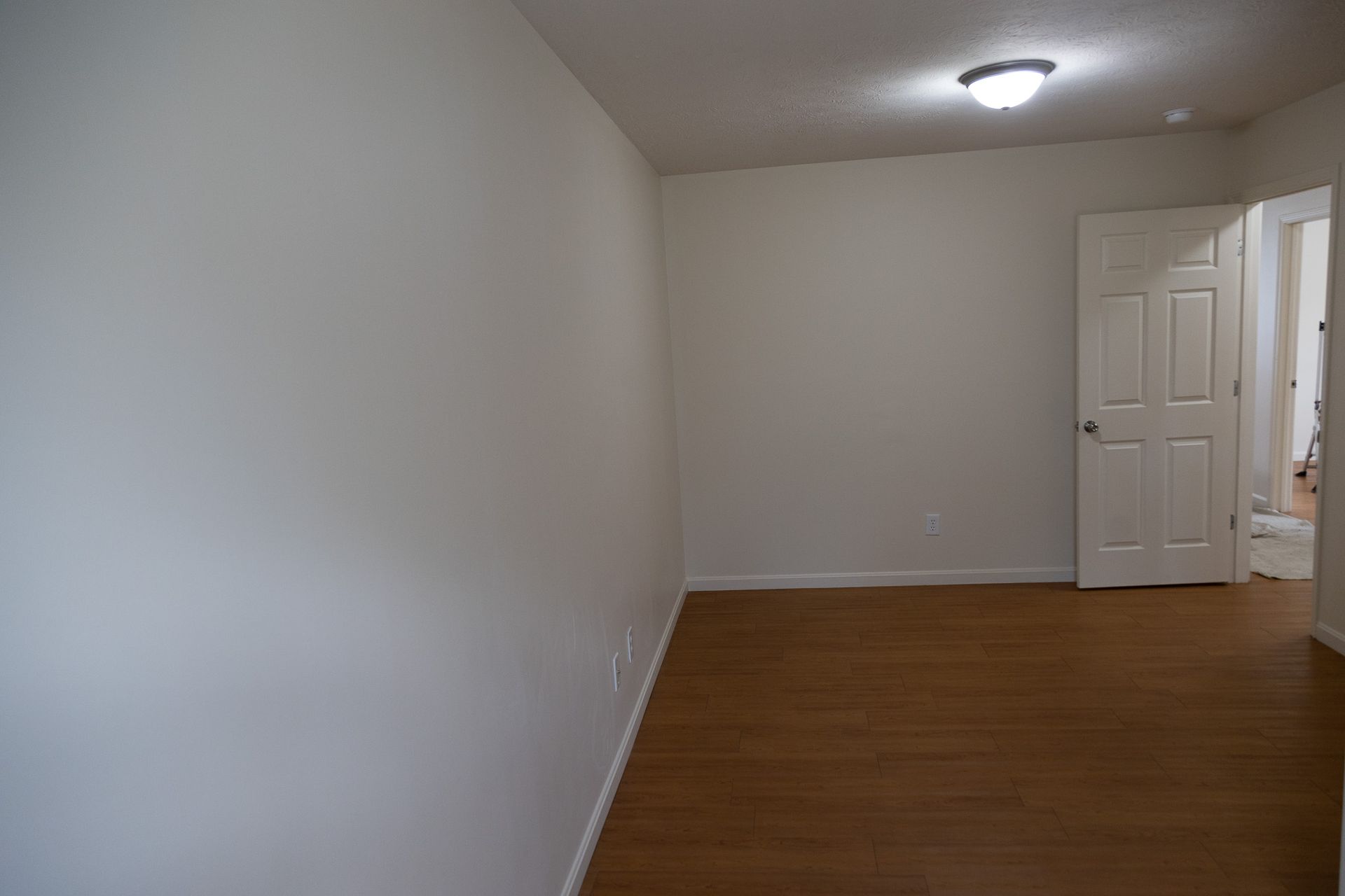 An empty room with a wooden floor and white walls
