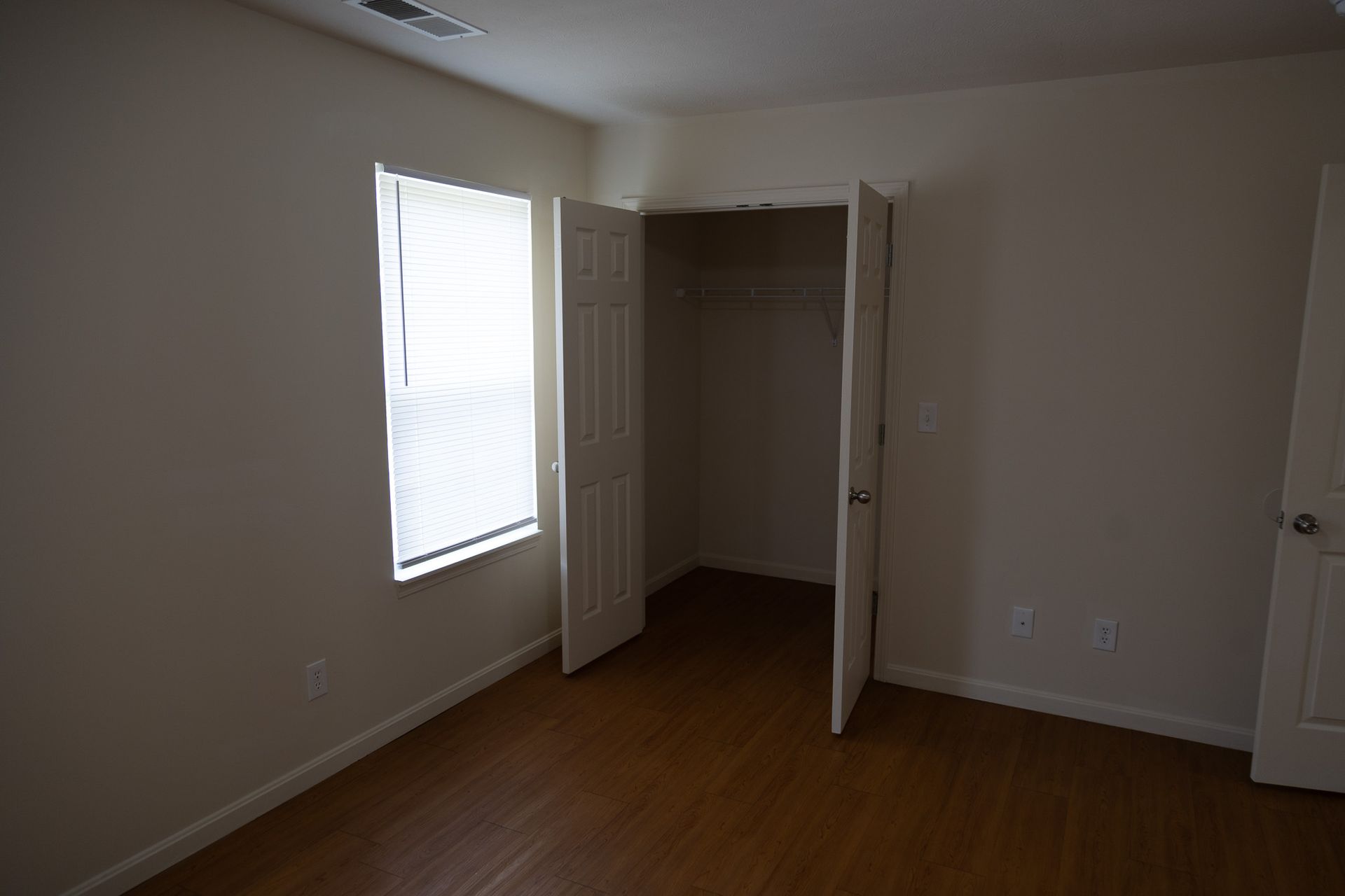 An empty bedroom with a closet and a window
