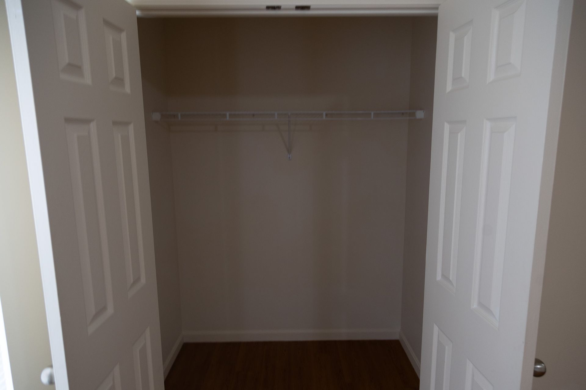 An empty closet with a wooden floor and white doors