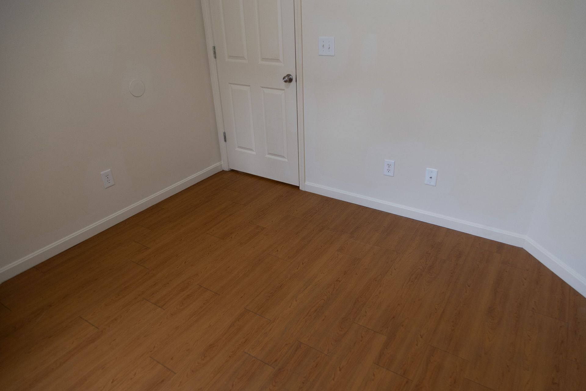 An empty room with wooden floors and white walls.
