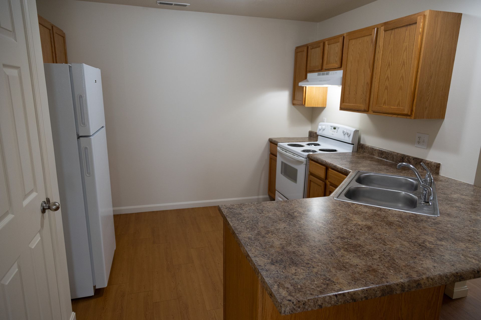 An empty kitchen with a refrigerator stove and sink