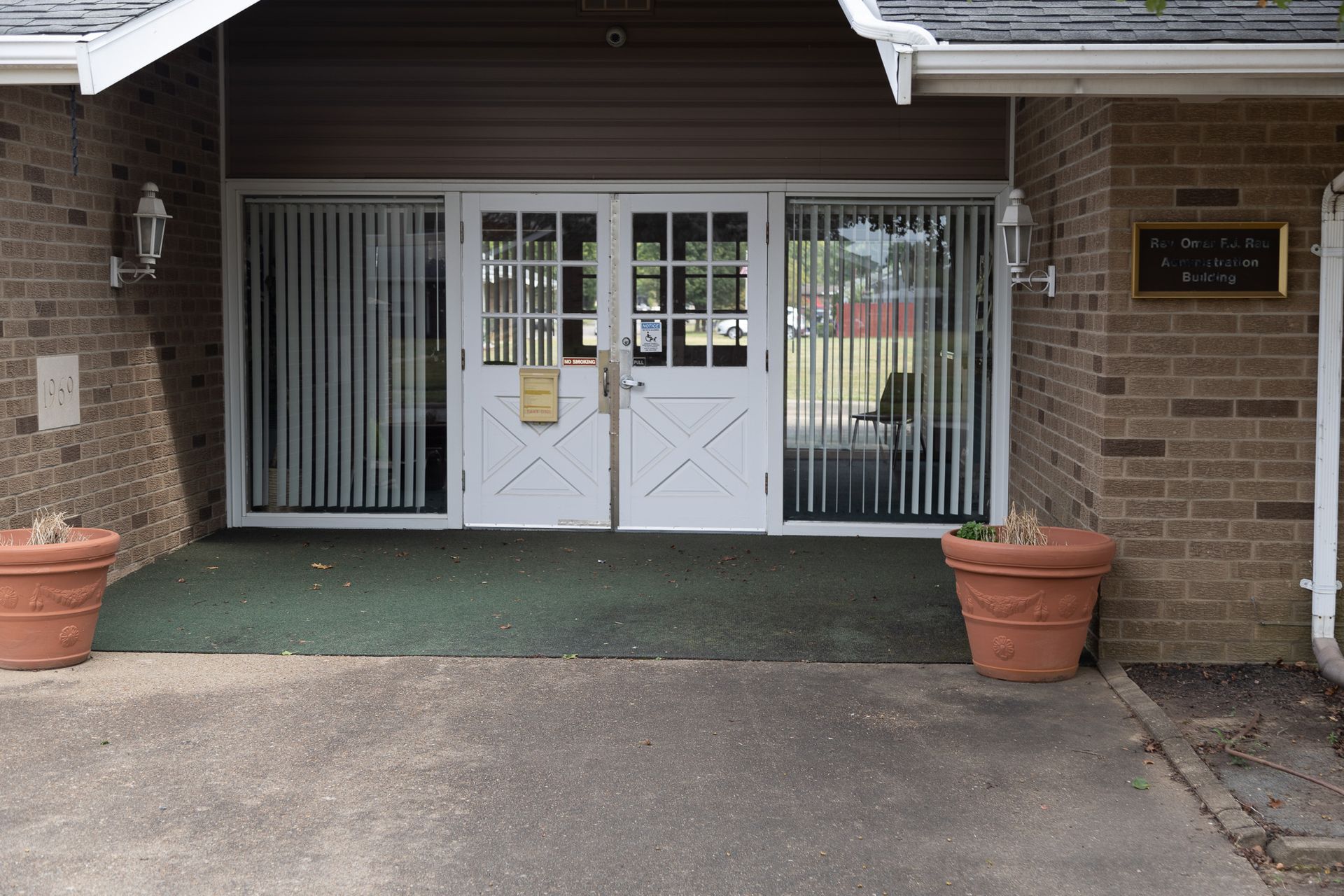 A brick building with white doors and potted plants in front of it