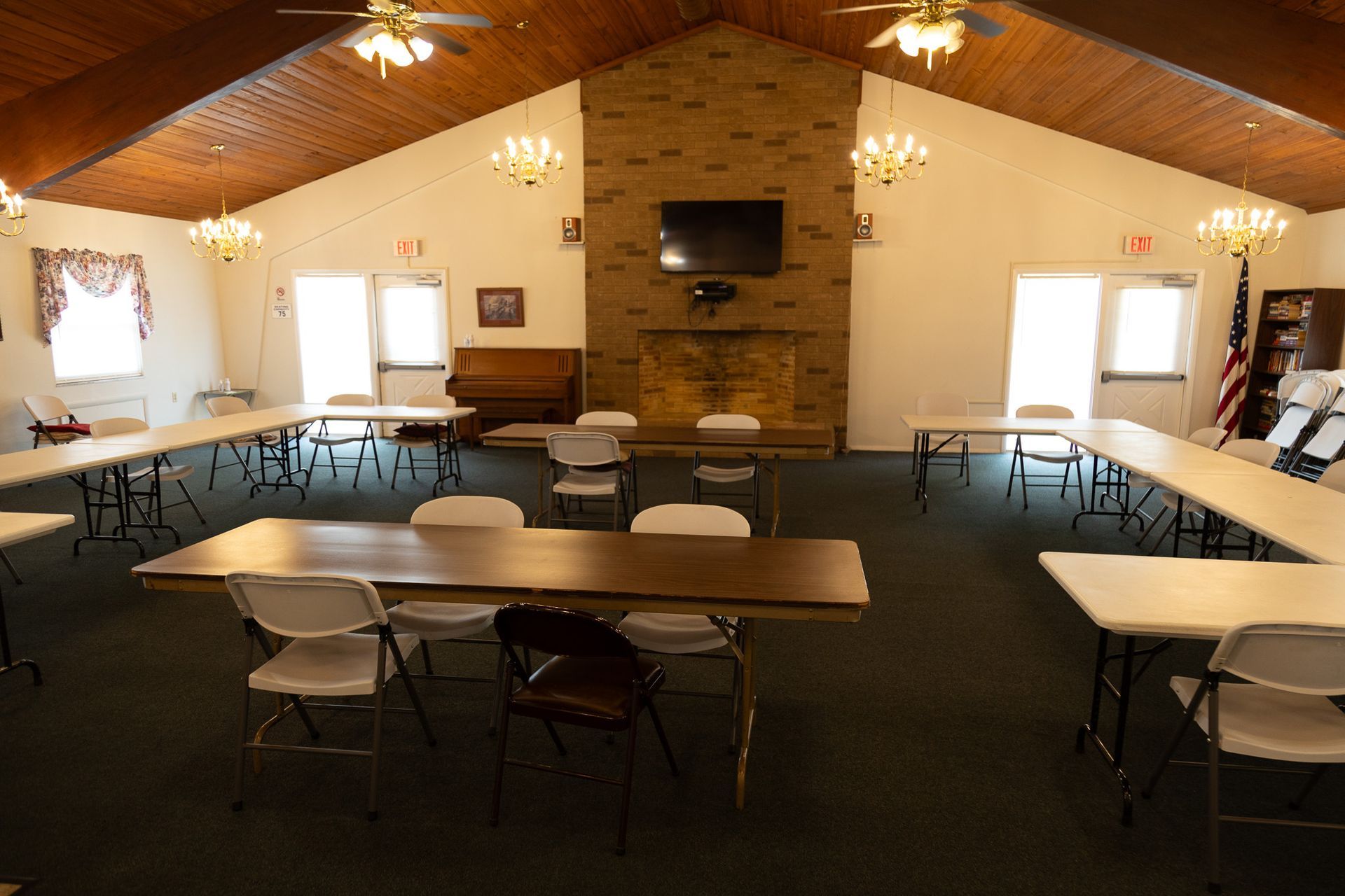 A large room with tables and chairs and a fireplace