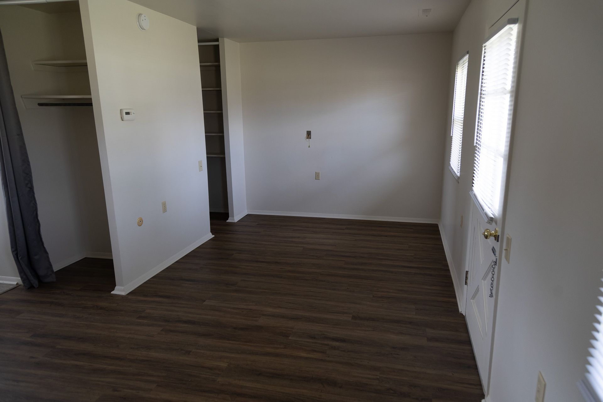 An empty living room with hardwood floors and white walls.