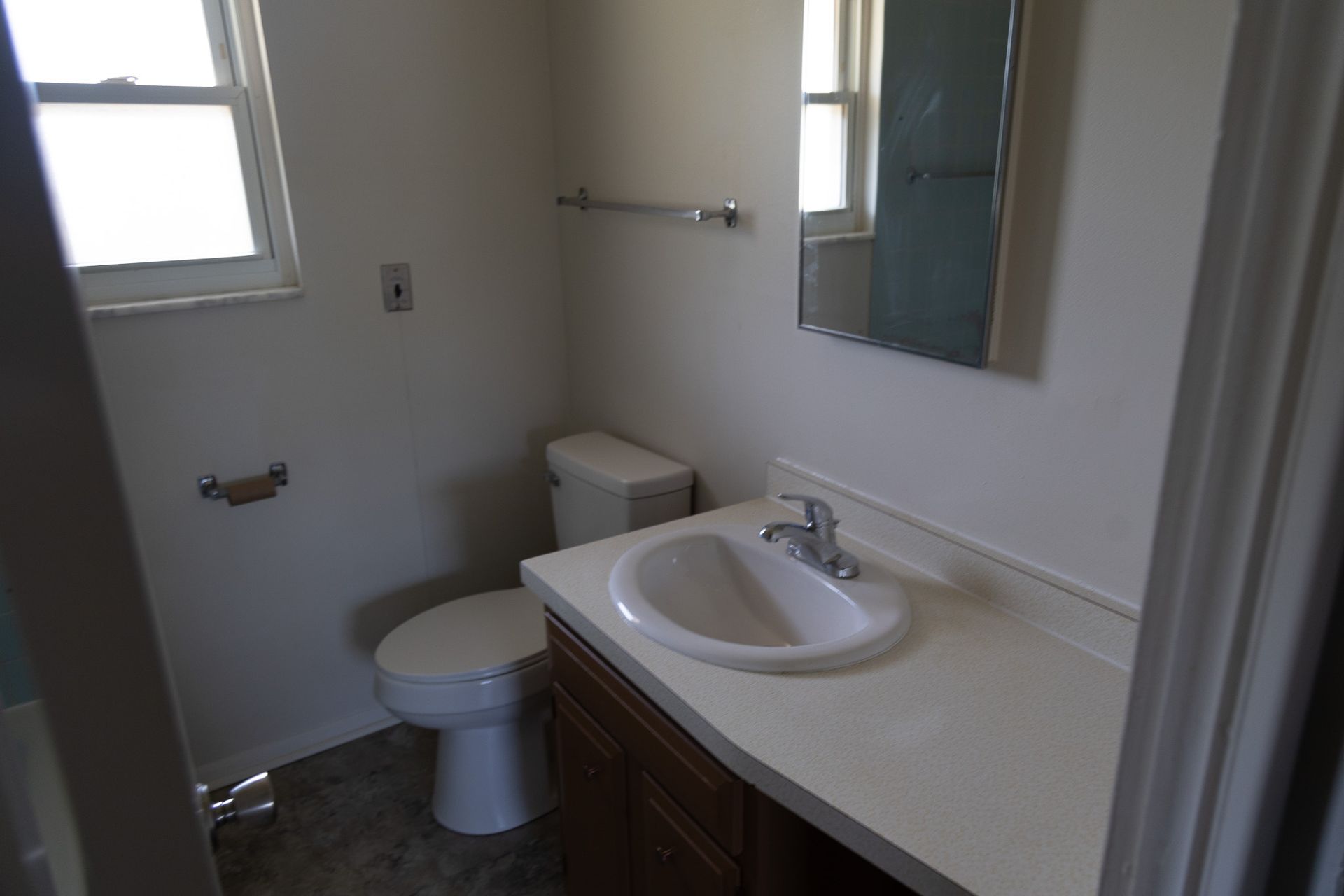 A bathroom with a toilet , sink and mirror.