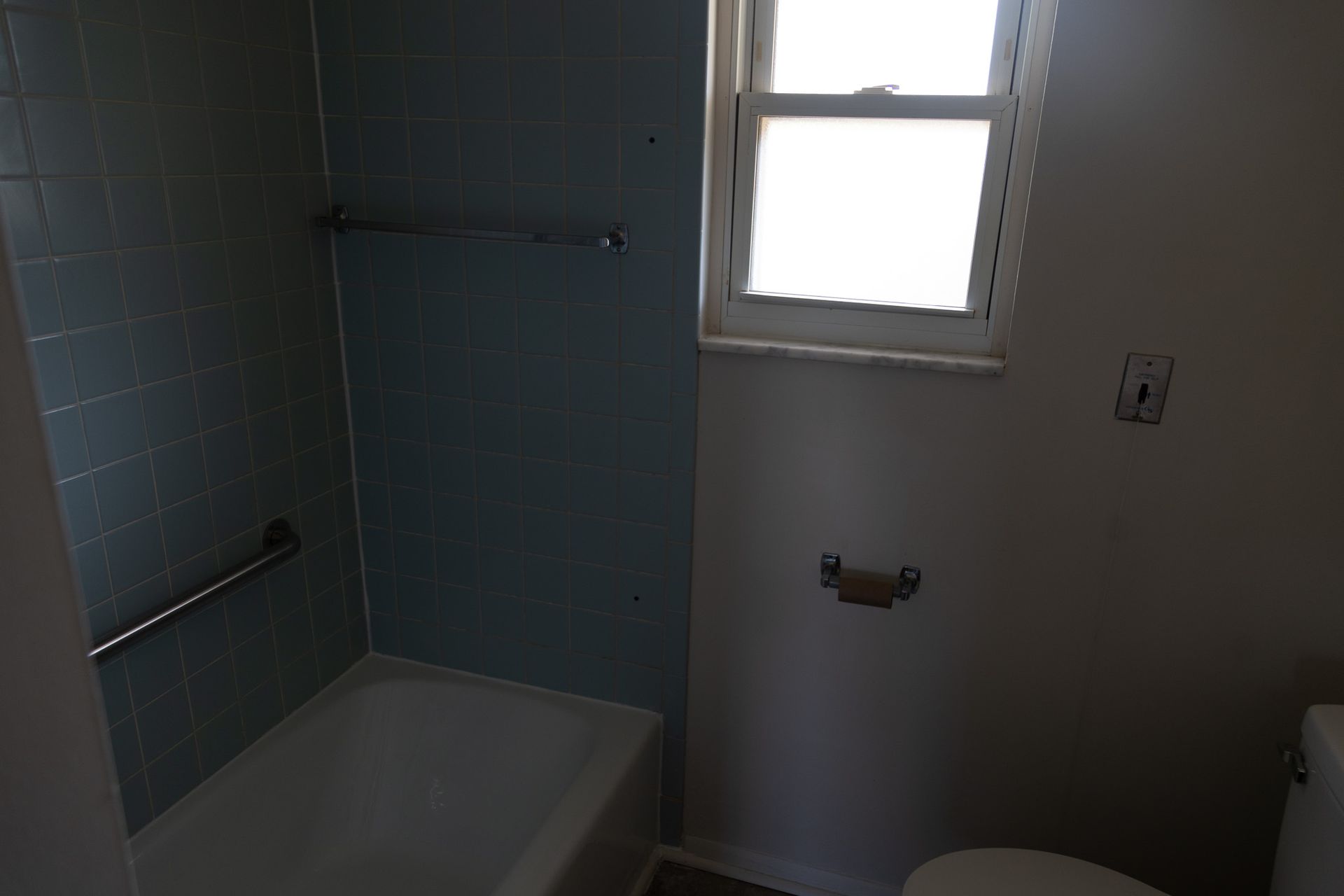 A bathroom with a tub , toilet and window.