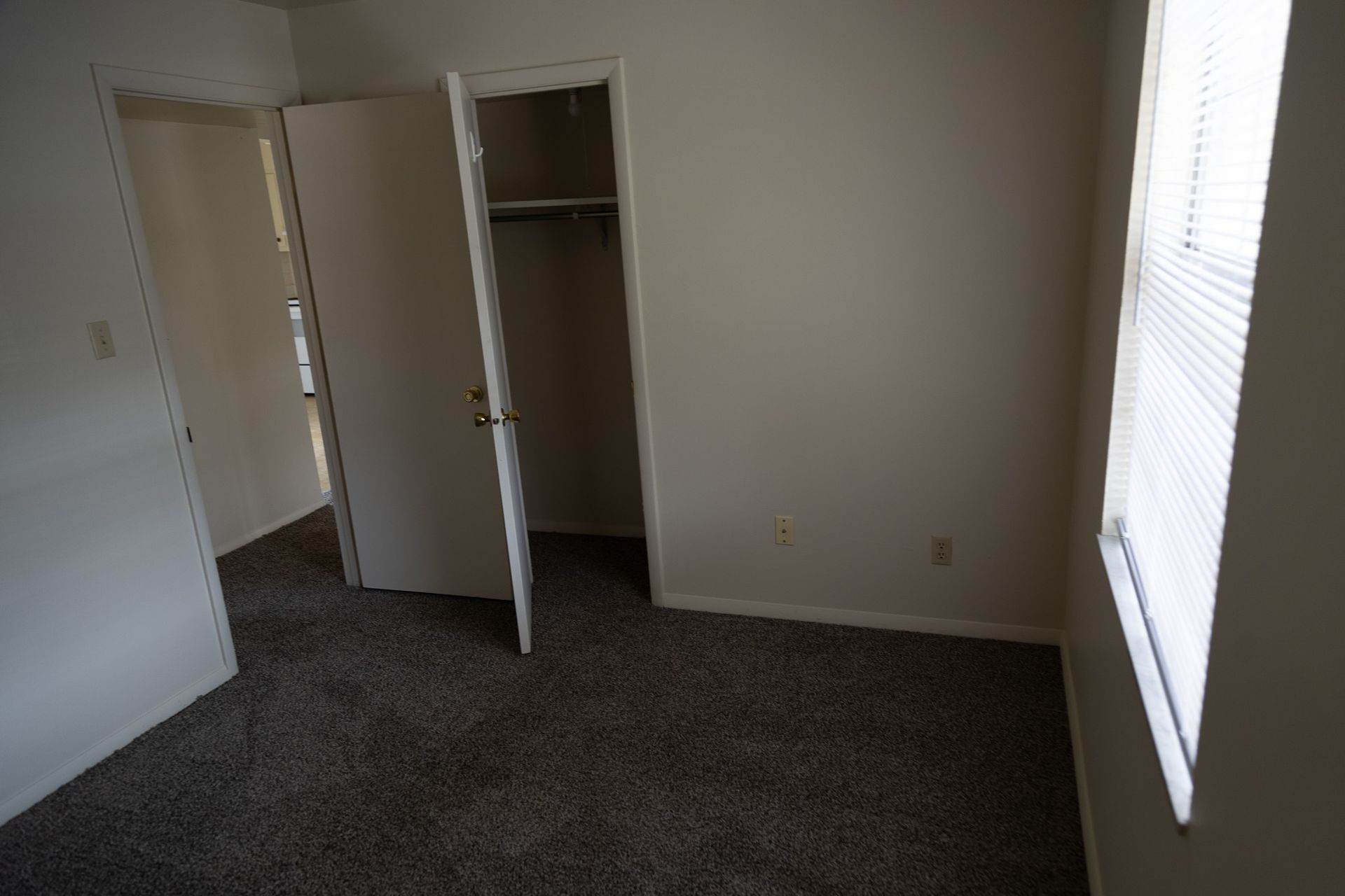 An empty bedroom with a closet and a window