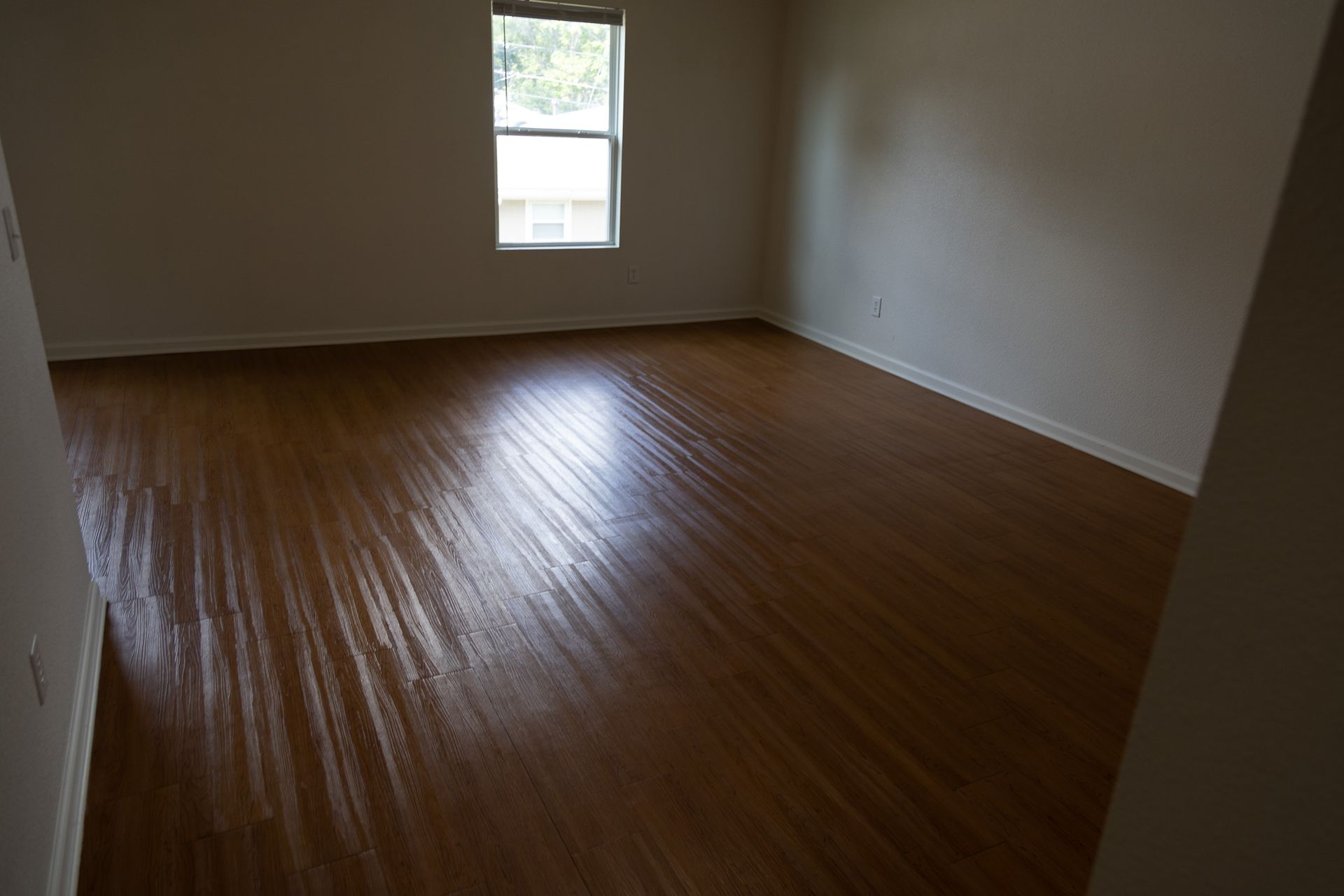 An empty room with a wooden floor and a window