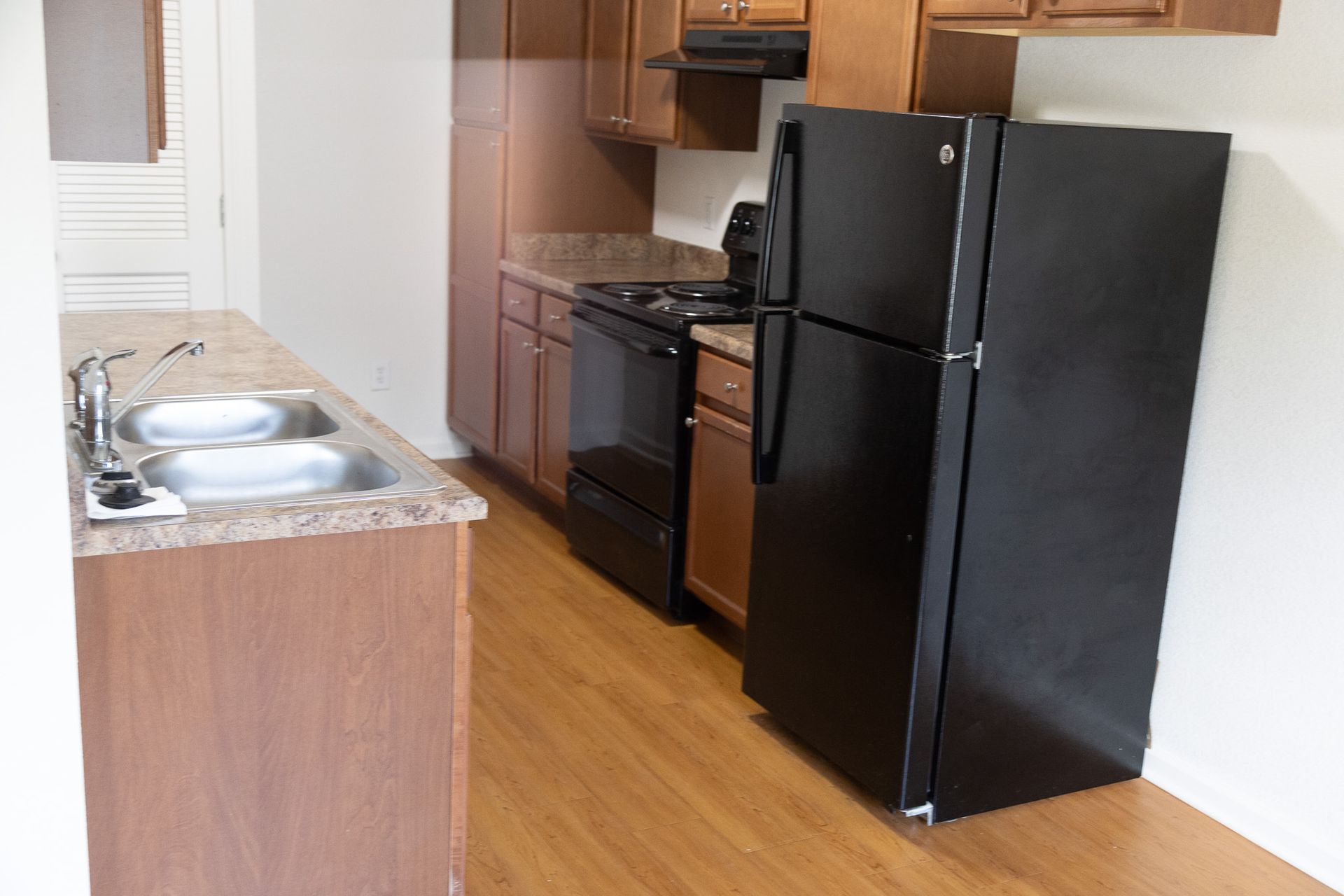 A kitchen with a black refrigerator , stove and sink.